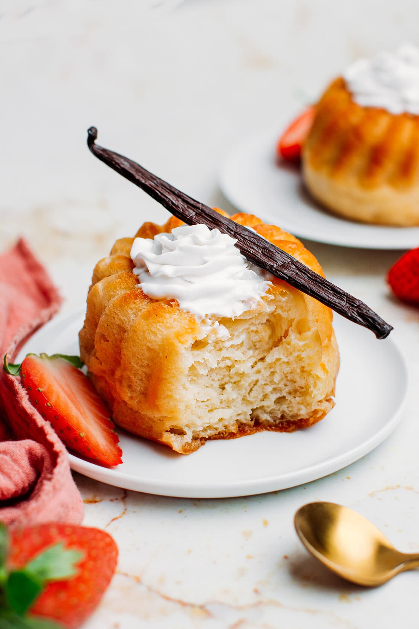 Rum baba topped with whipped cream, strawberries, and vanilla bean.