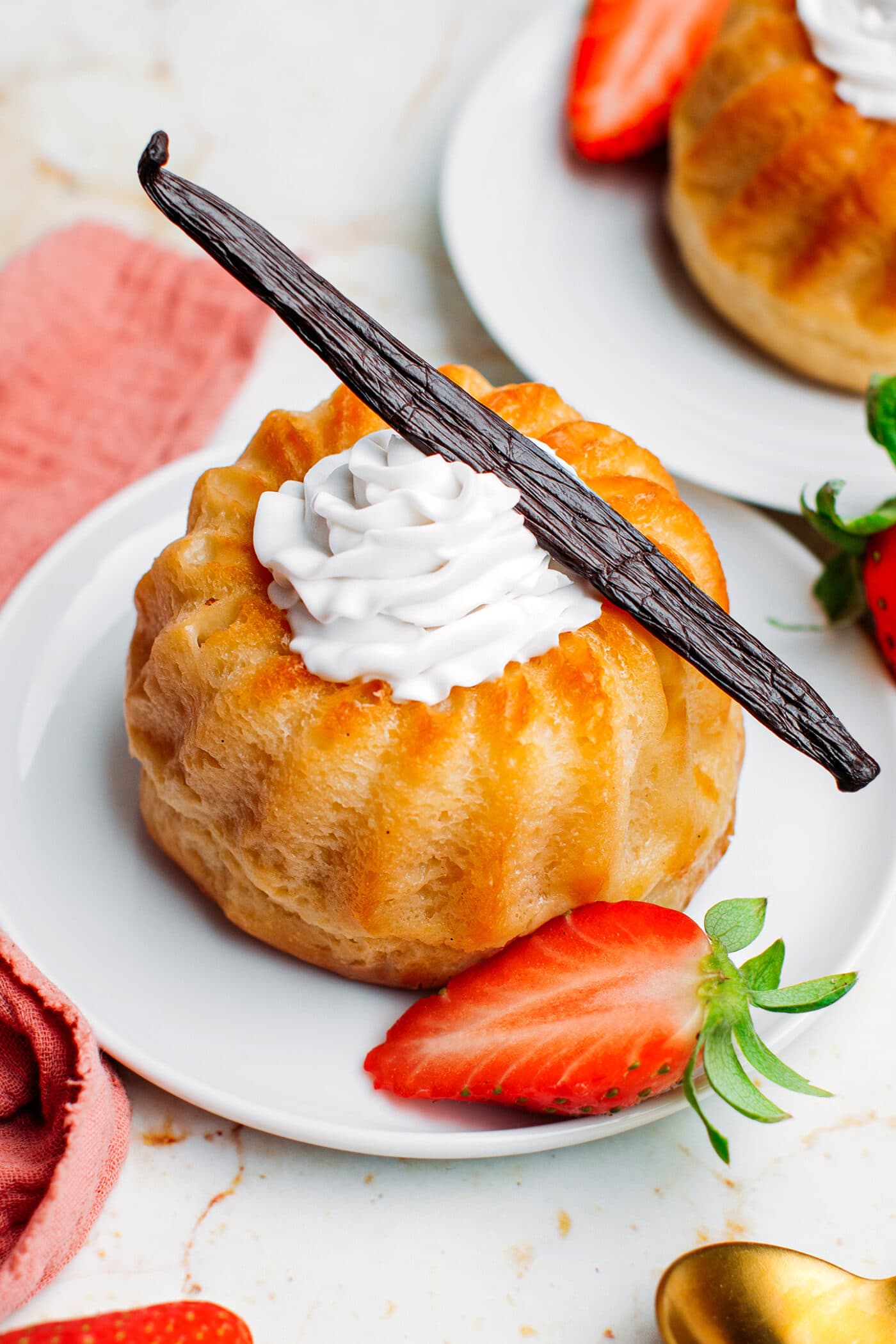 Rum baba topped with whipped cream, strawberries, and vanilla bean.