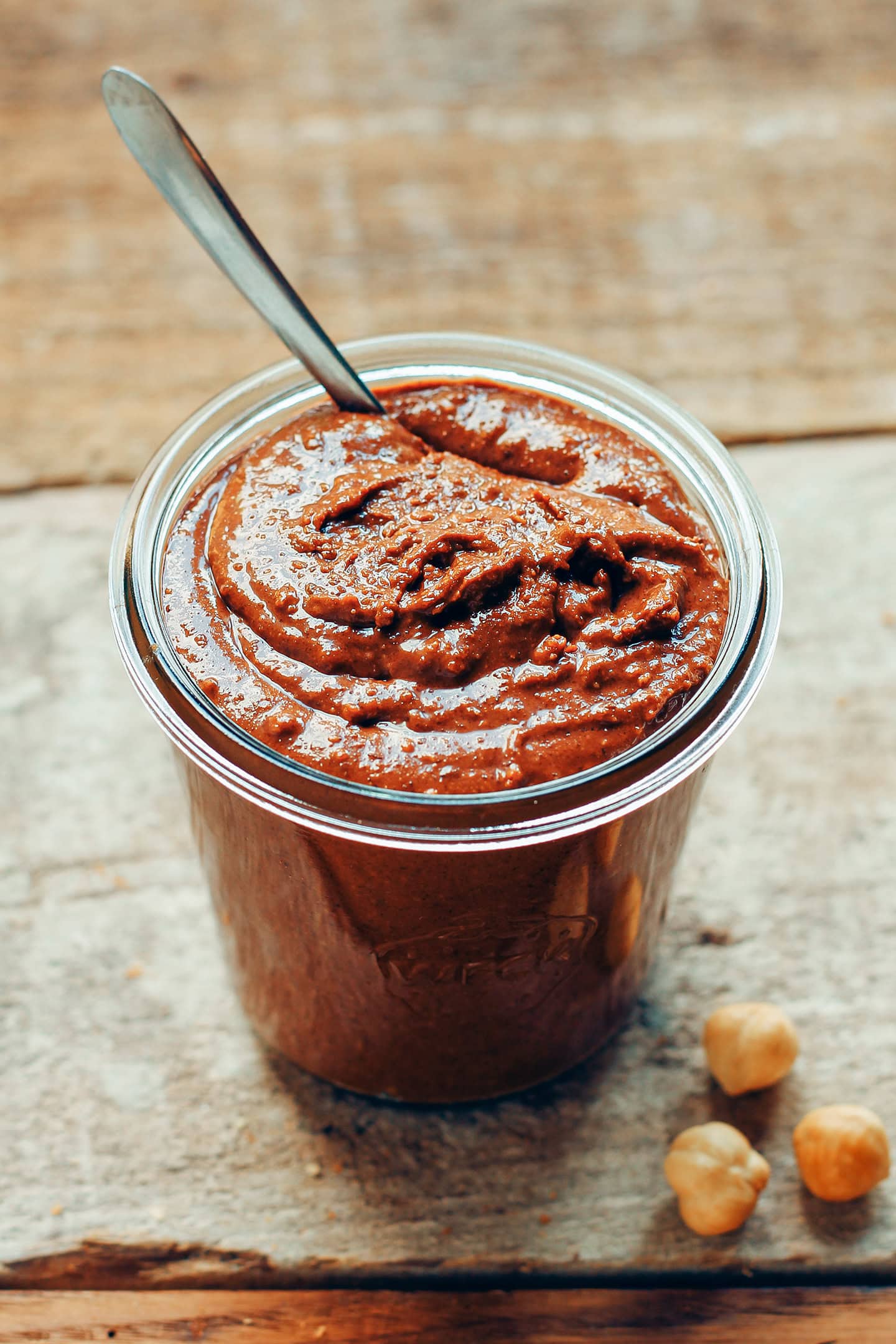 Jar of chocolate praline spread on a wooden board.