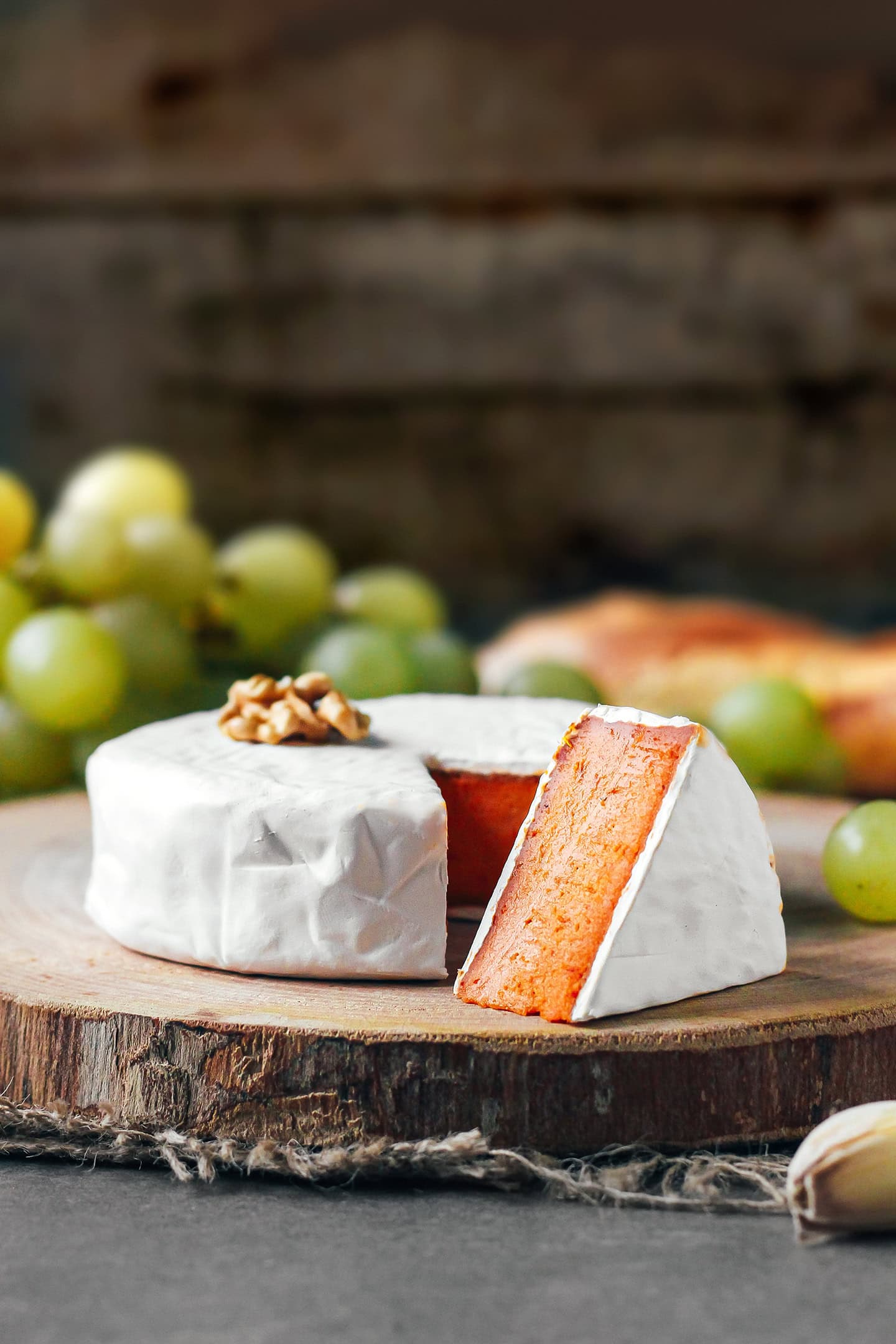 Sliced sun-dried tomato camembert on a wooden board.