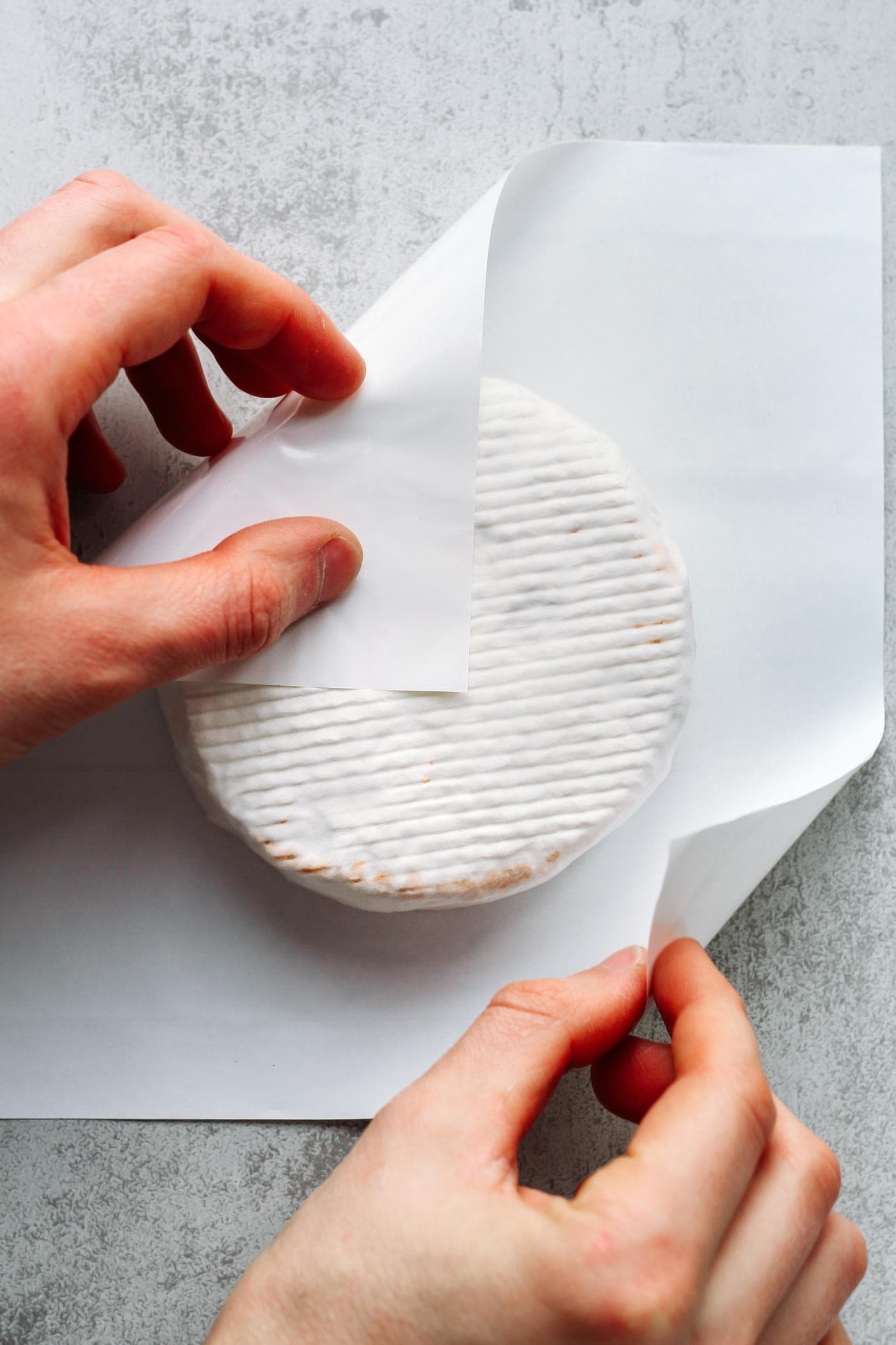 Wrapping a vegan camembert cheese with cheese paper.