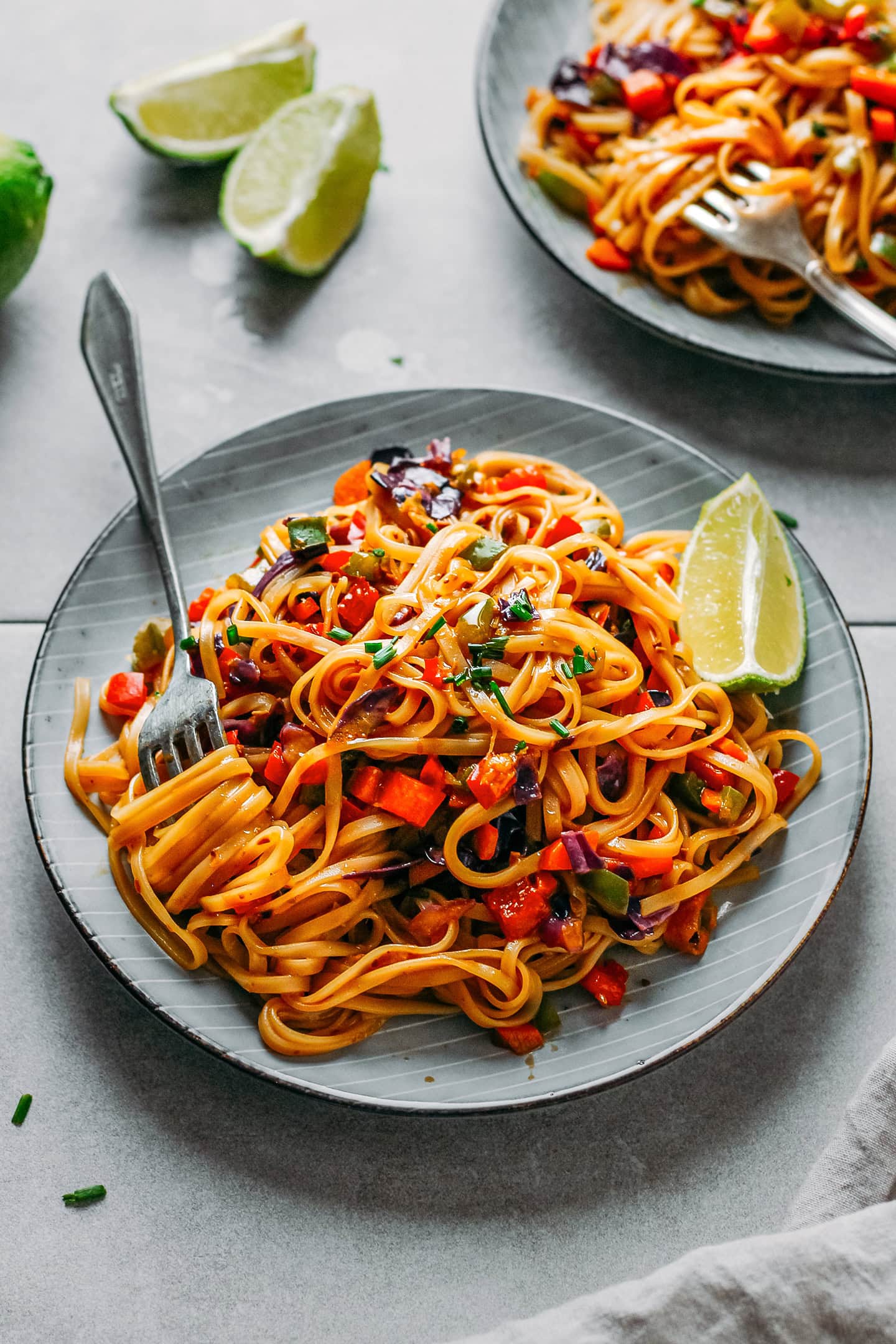Sautéed noodles with vegetables and lime on a plate.