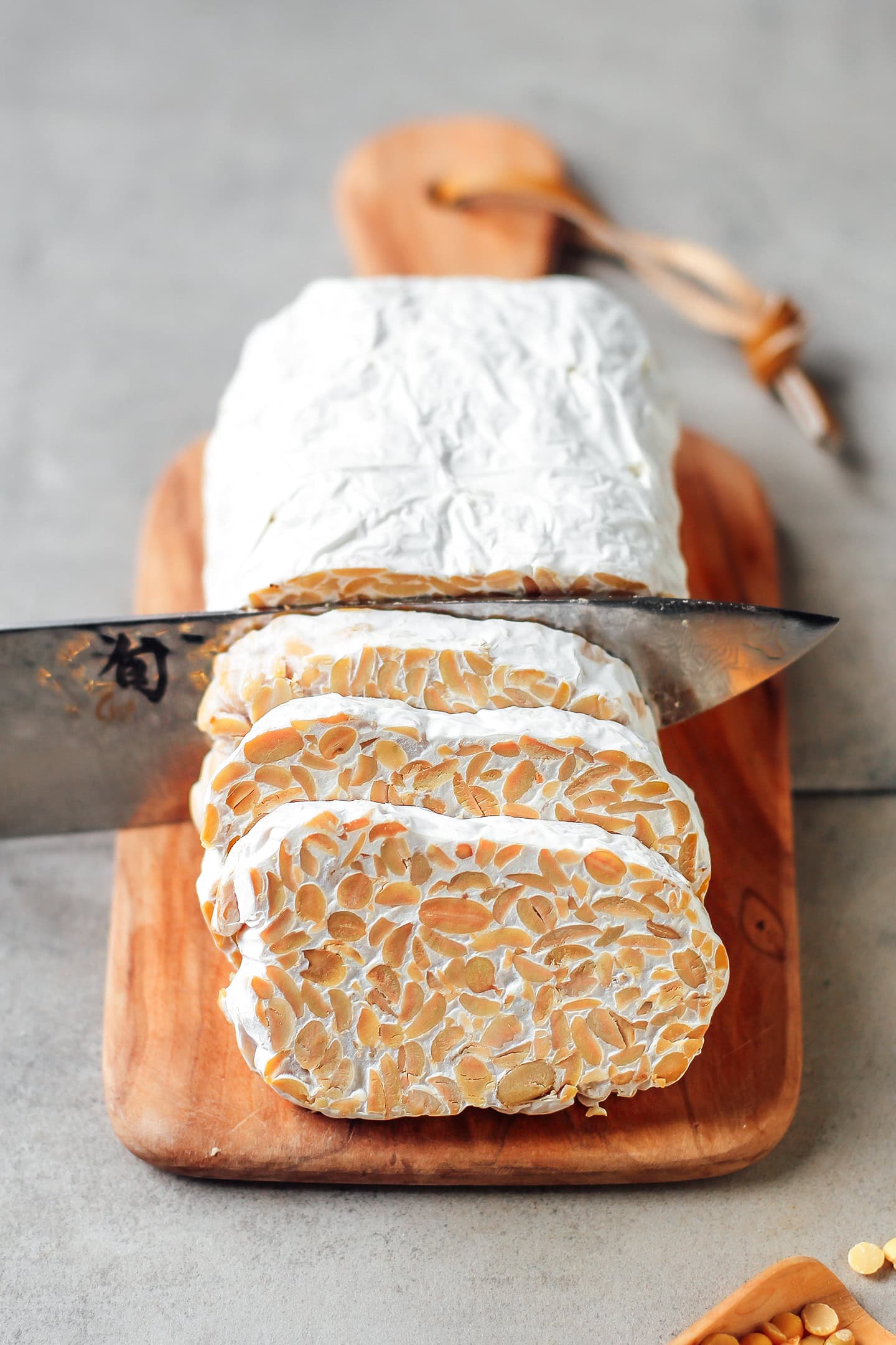 Sliced loaf of tempeh on a wooden board.