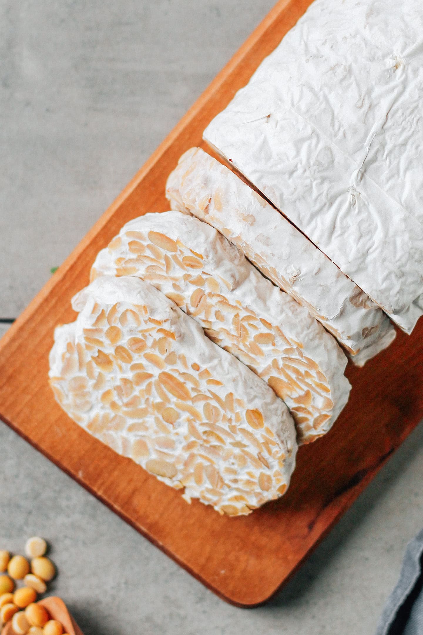 Loaf of sliced soybean tempeh on a wooden board.