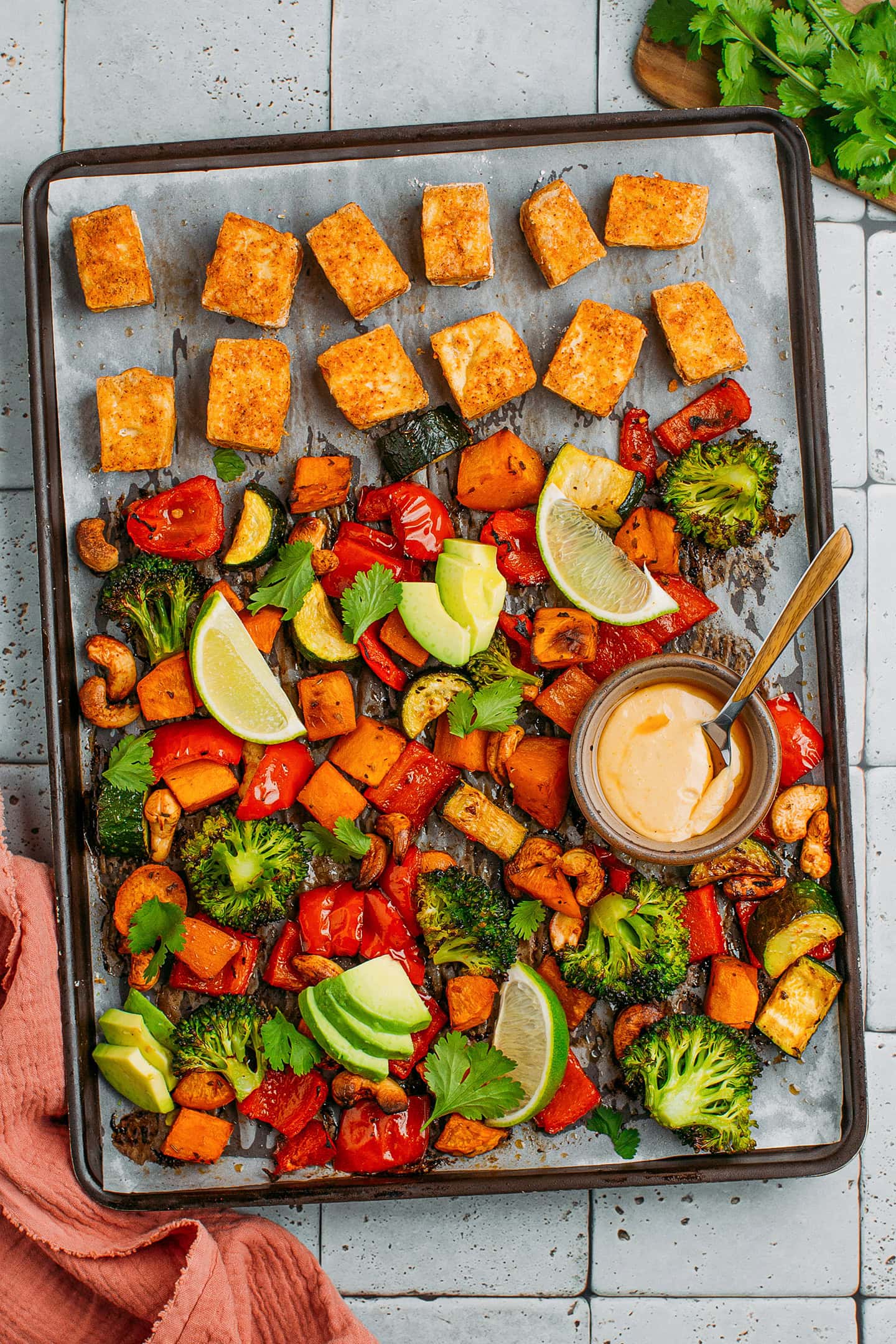 Sheet pan with roasted sweet potatoes, broccoli, zucchini, cashews, and tofu.