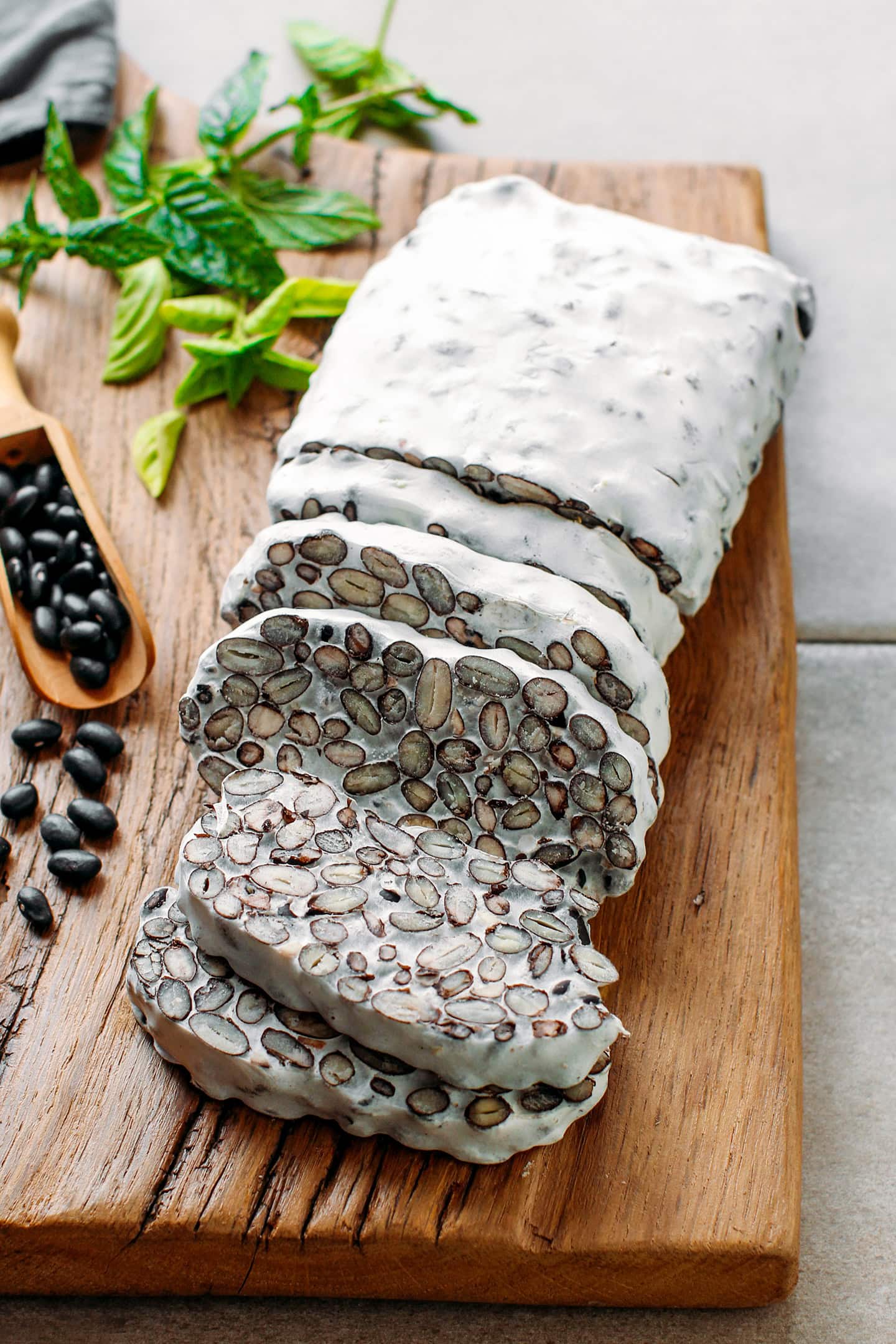 Sliced loaf of black bean tempeh on a wooden cutting board.