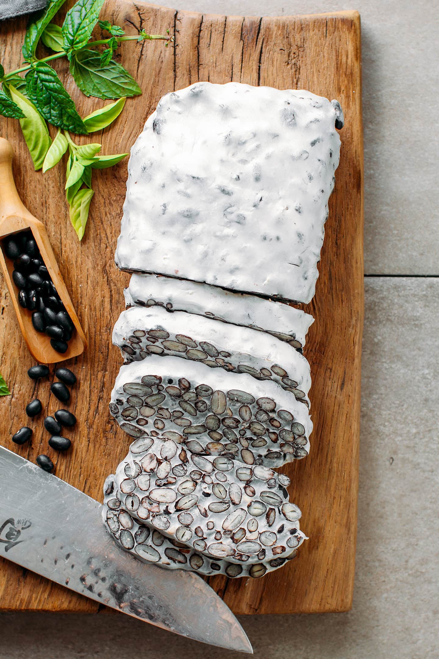 Sliced loaf of black bean tempeh on a wooden board.