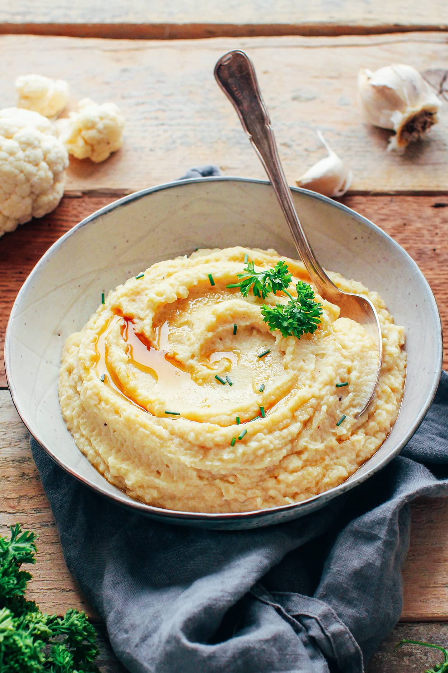 Mashed celery root and cauliflower garnished with scallions and parsley in a bowl.