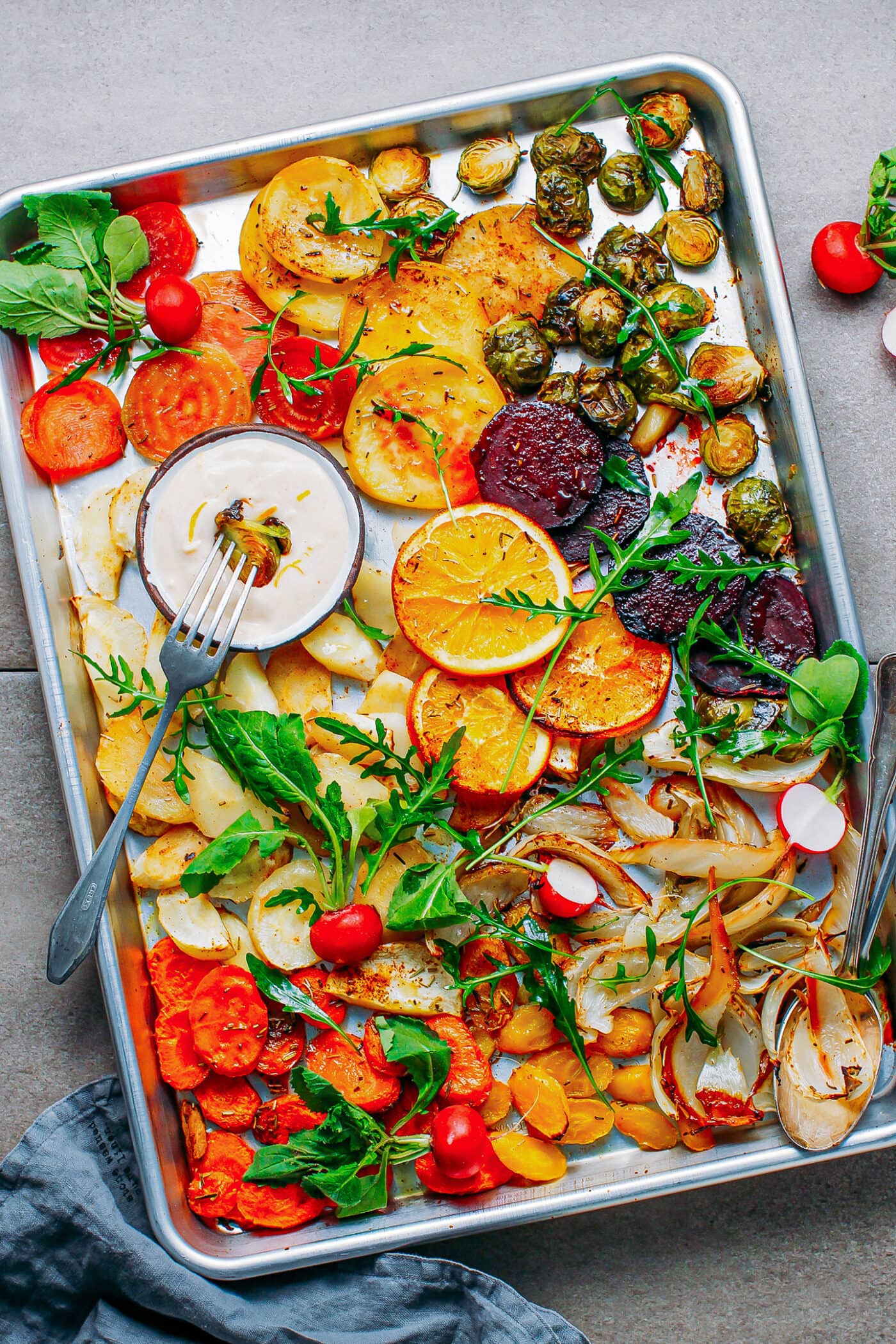Roasted vegetables like beets, fennel, parsnips, and carrots, on a baking sheet.