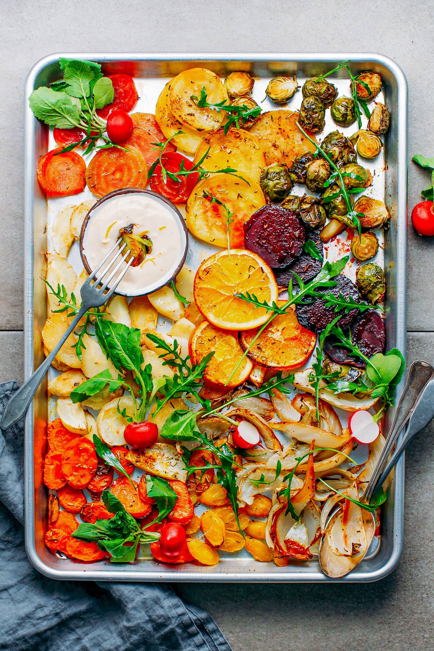 Roasted vegetables like beets, fennel, parsnips, and carrots, on a baking sheet.