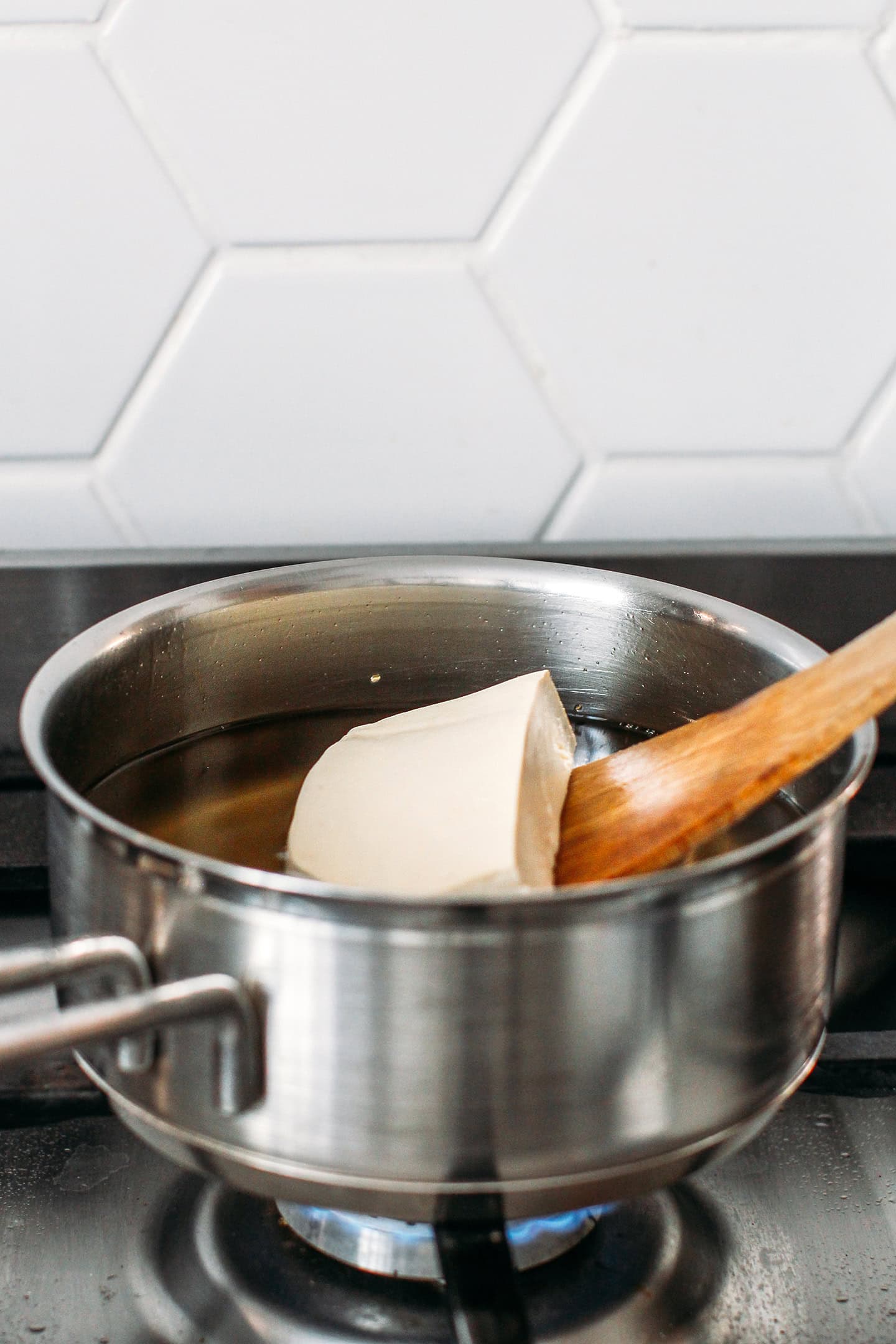 Placing a block of tofu in a pot of oil.