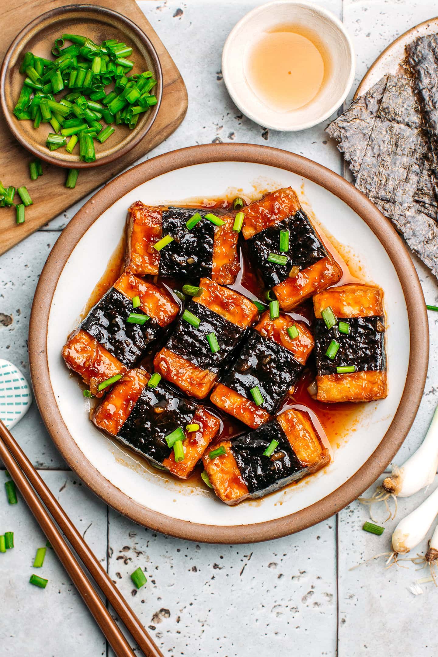 Tofu wrapped with seaweed and served in a lemongrass sauce in a small plate.