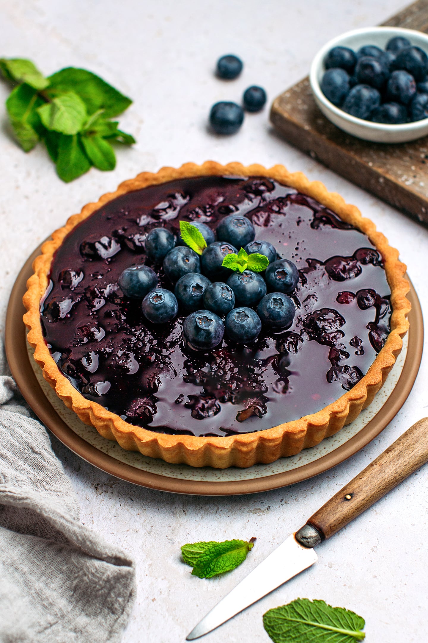 Vegan blueberry tart topped with fresh blueberries on a plate.