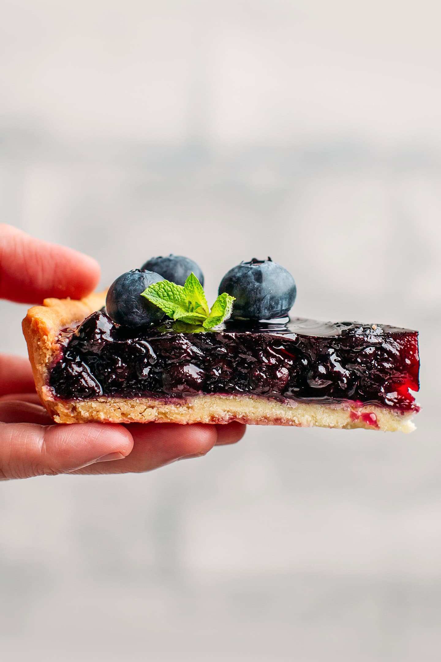 Holding a slice of blueberry tart.