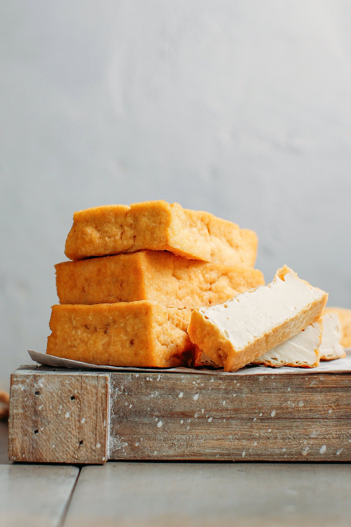 Blocks of deep-fried tofu stacked on a wooden board.