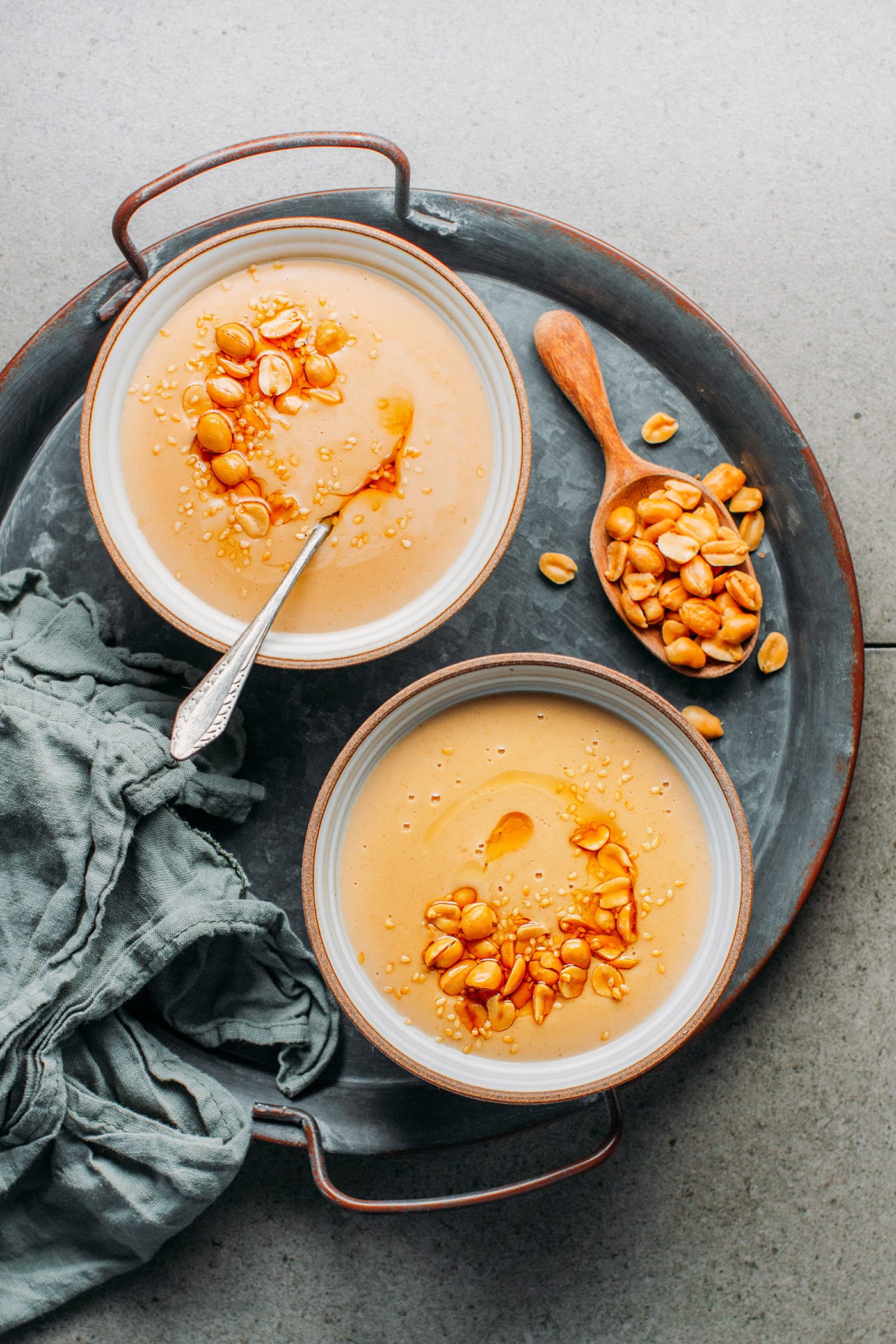 Two bowls of peanut soup on a metal platter.