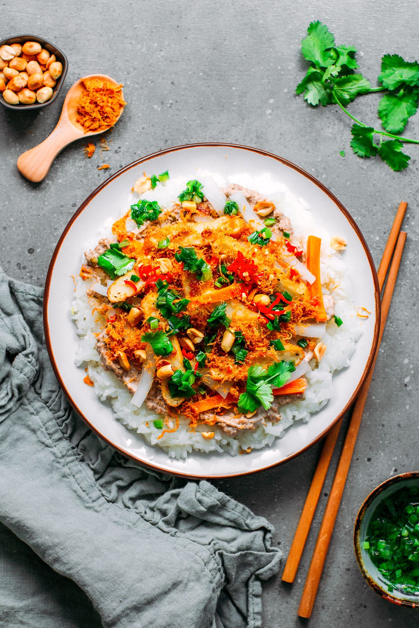 Top view of a plate filled with rice and topped with meat floss, green onions, and pickles.