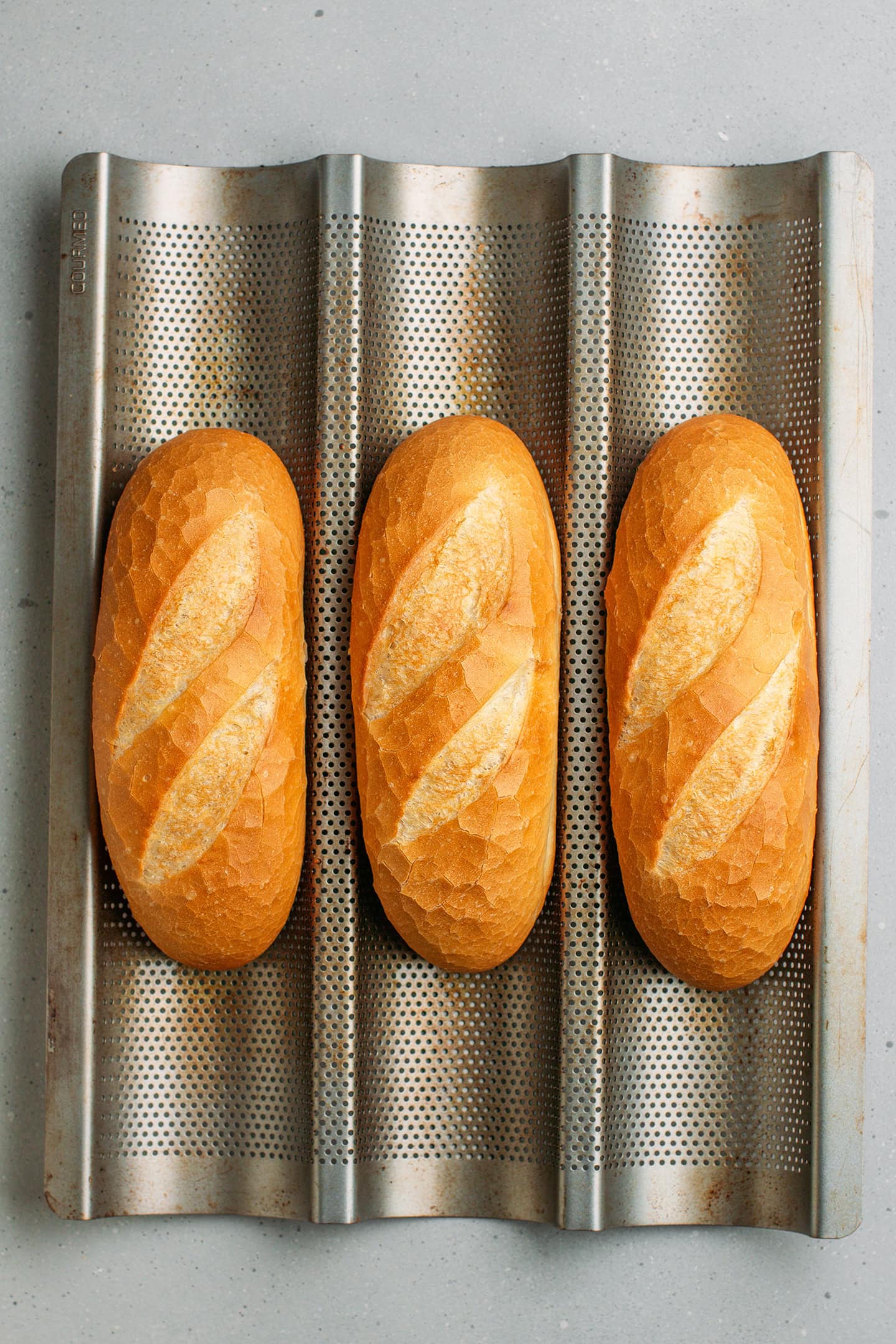 Three banh mi baguettes on a pan.