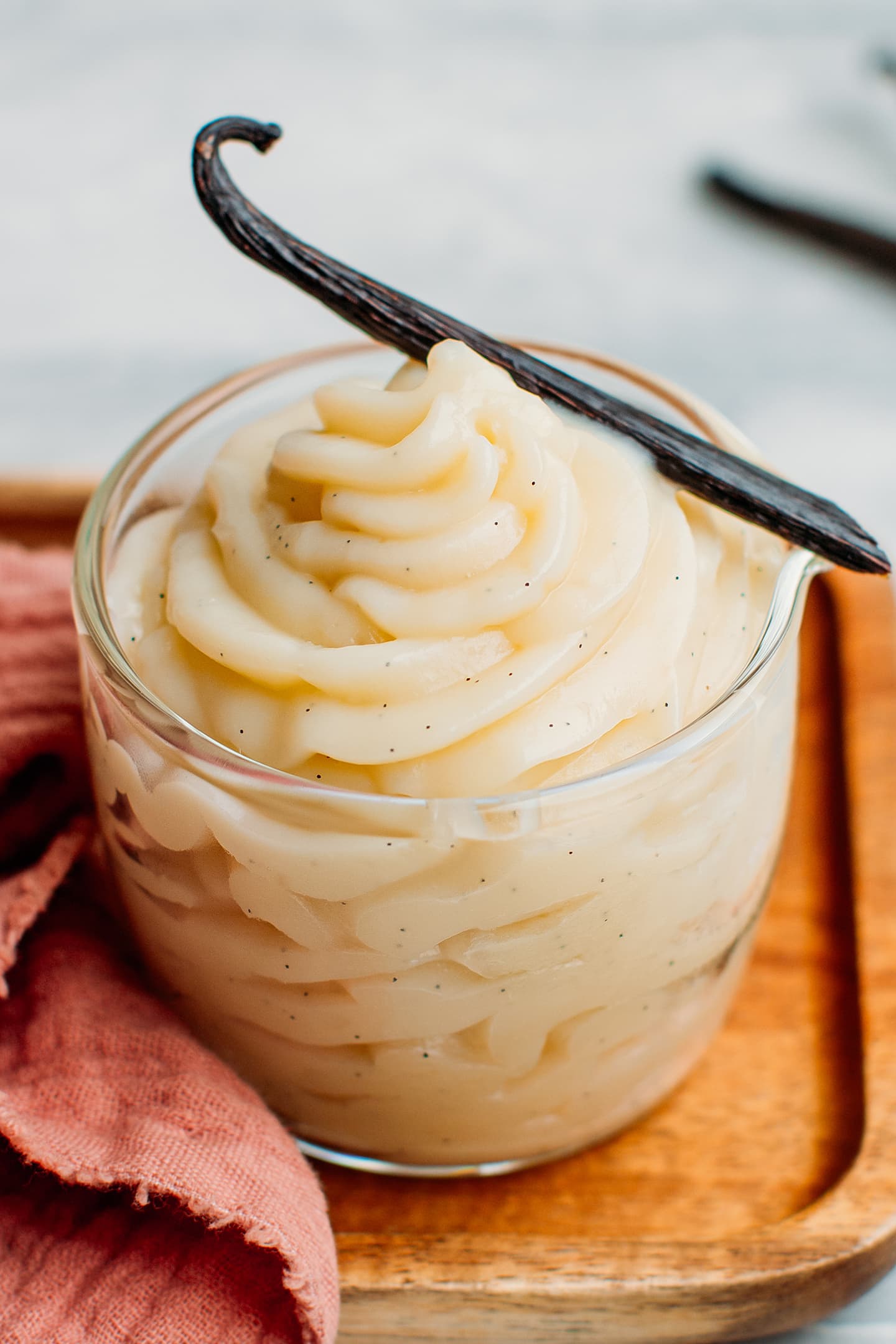 Vanilla pastry cream and vanilla bean pod in a glass container.