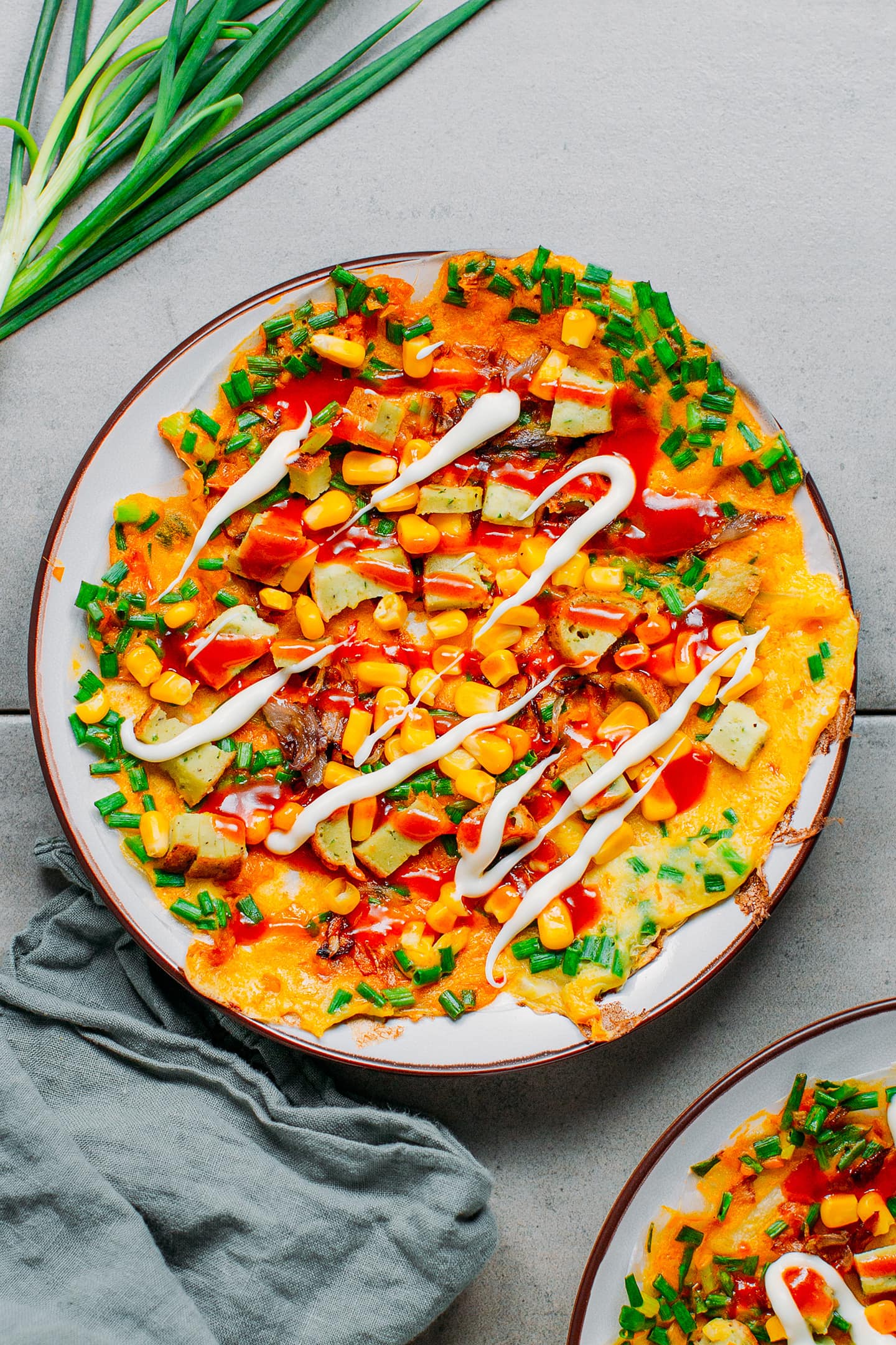 Grilled rice paper topped with corn, sausages, green onions, and drizzled with mayo and chili sauce.