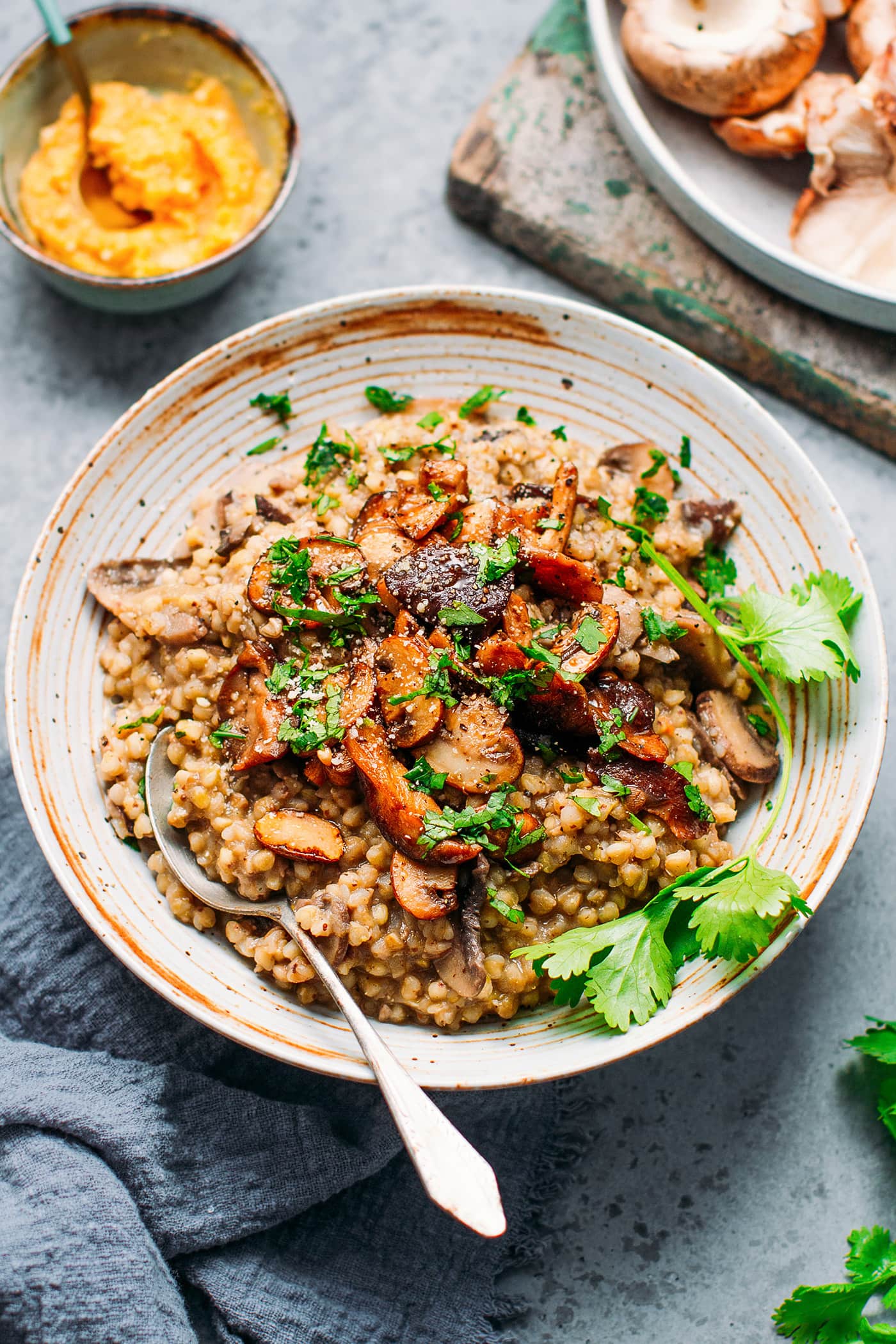 Buckwheat risotto topped with mushrooms and chopped cilantro in a bowl.