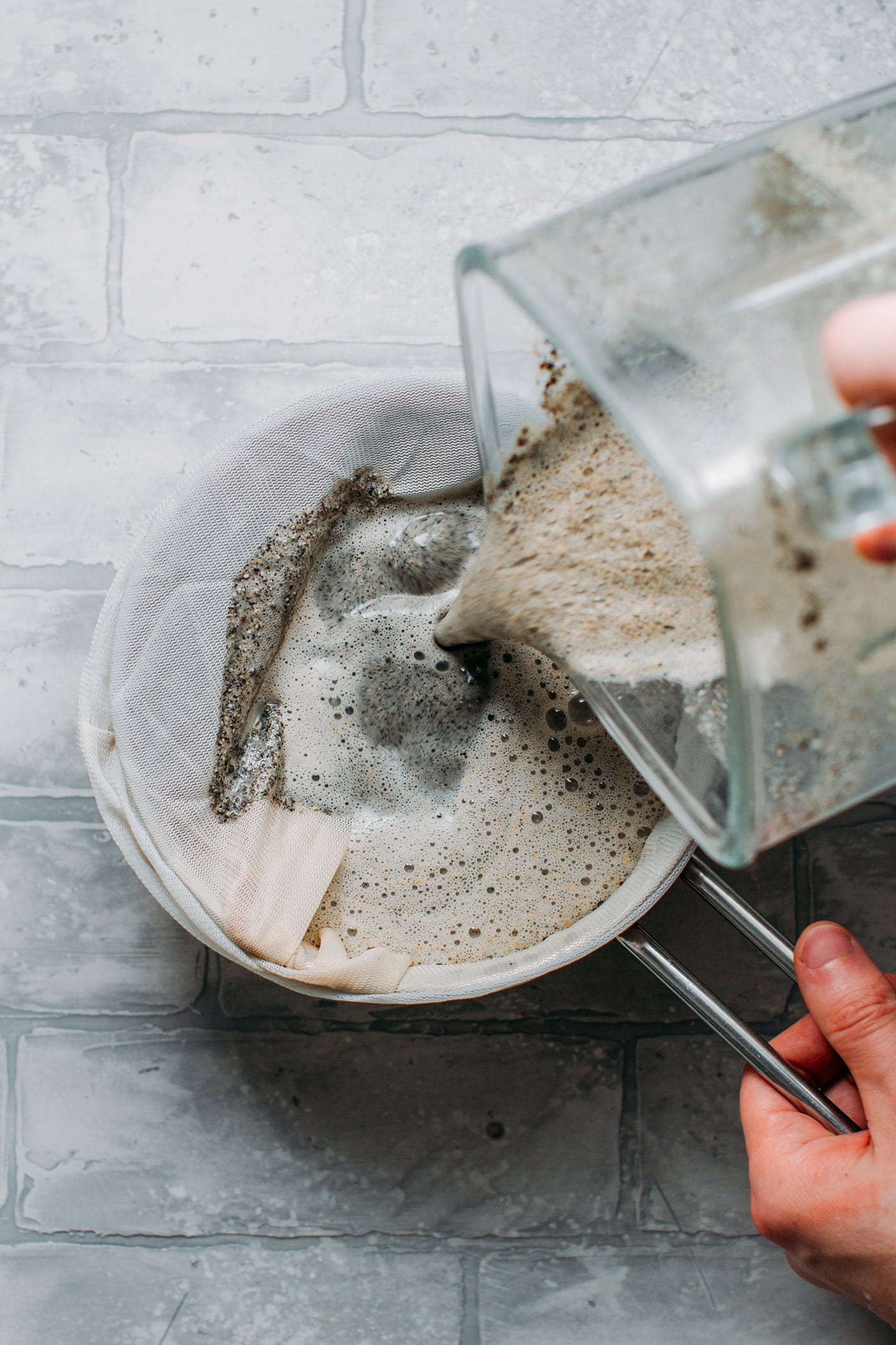Pouring black sesame milk into a nut milk bag.