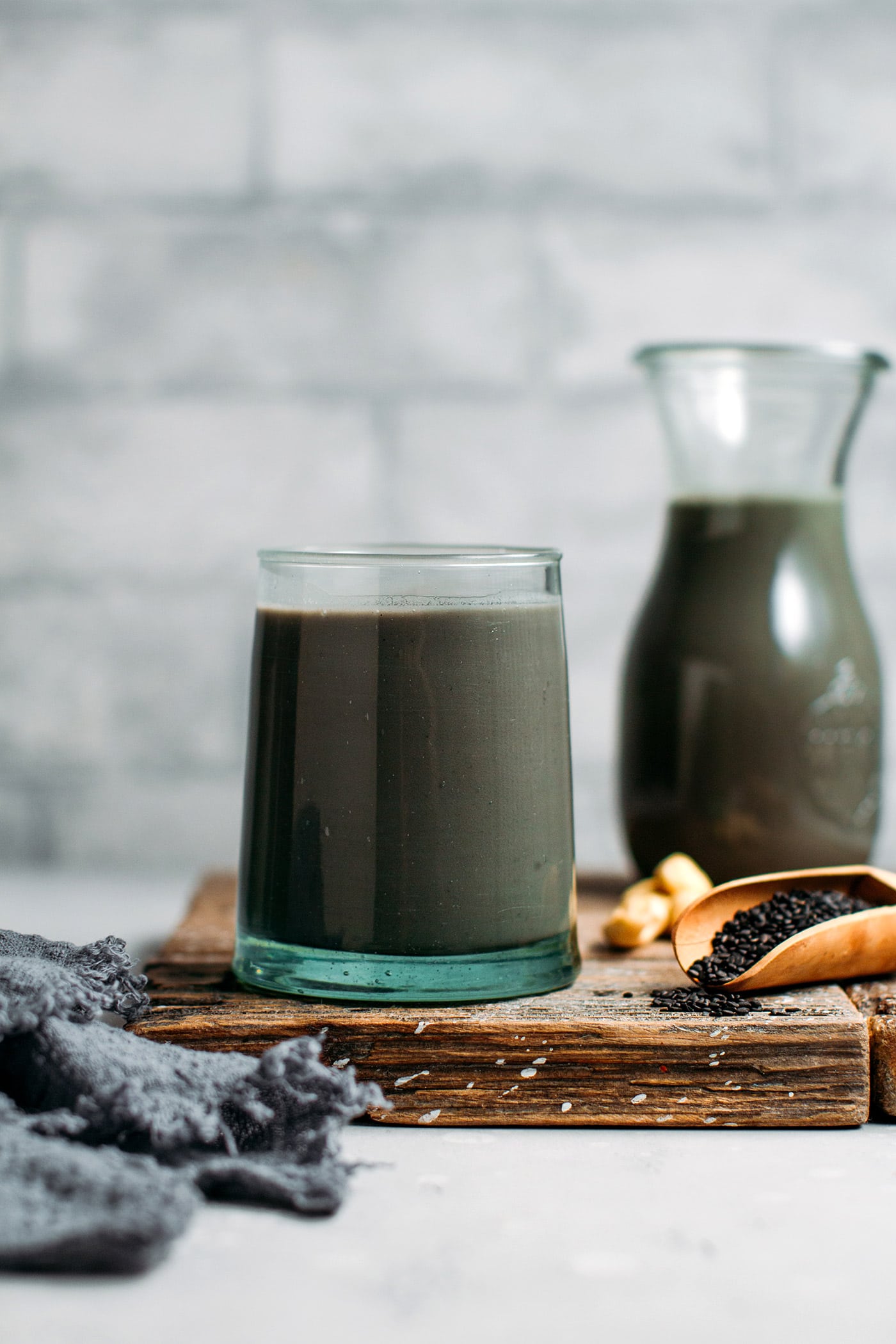 Glass of black sesame milk on a wooden board.
