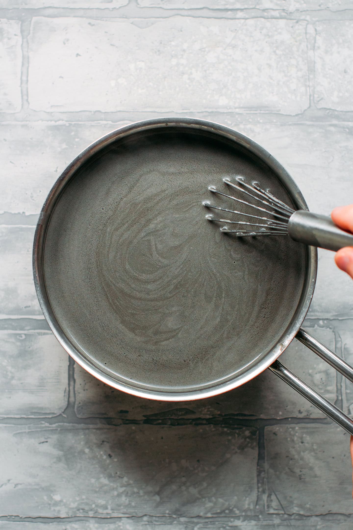 Whisking black sesame milk in a saucepan.