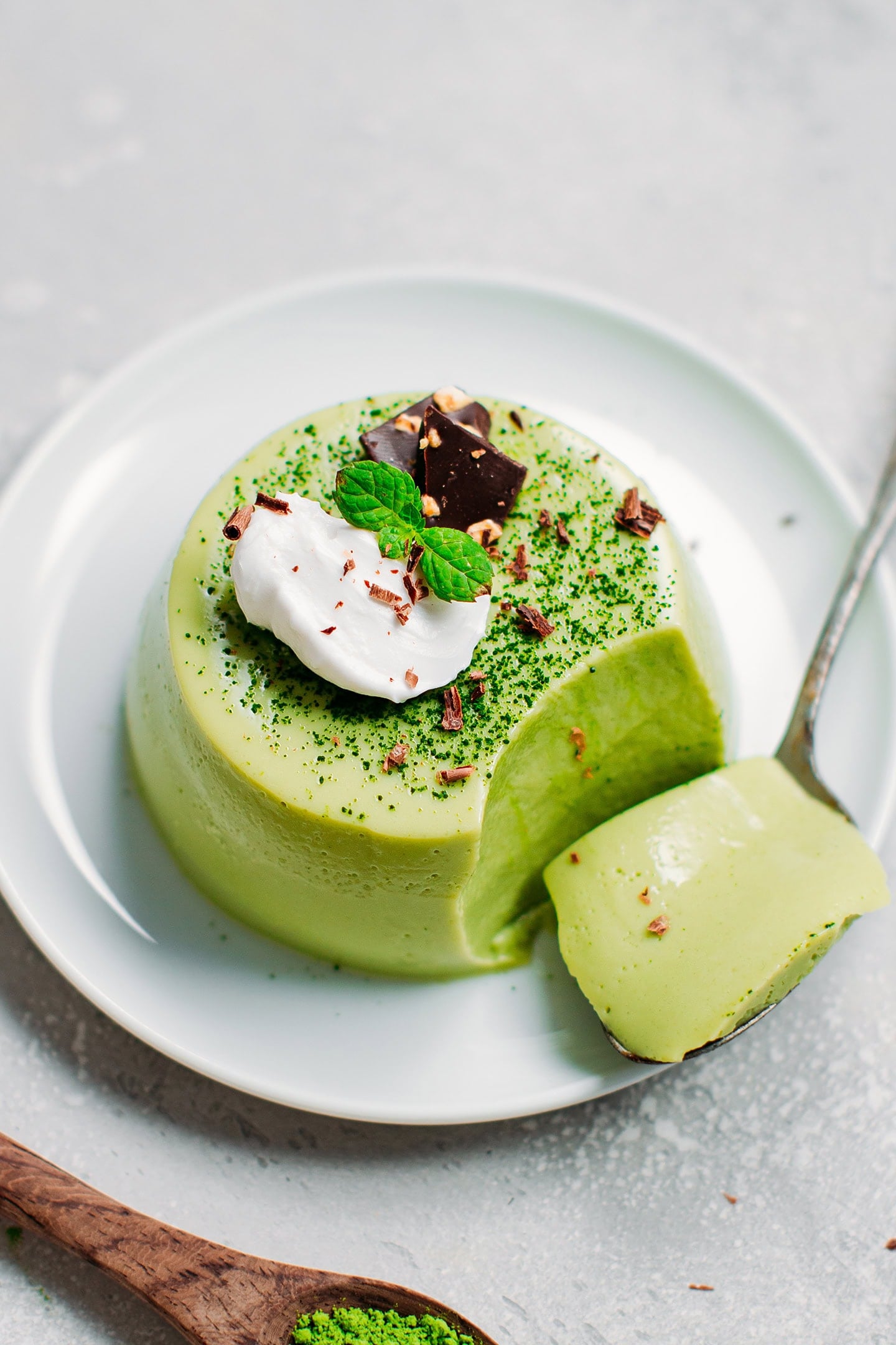 Matcha panna cotta topped with chocolate shavings, coconut cream, and mint.