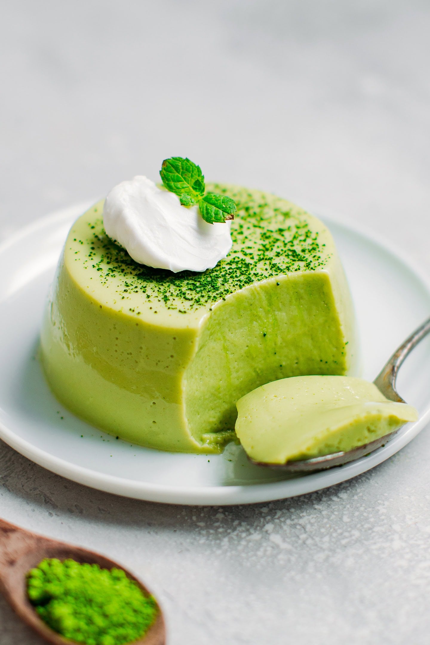 Close-up of a vegan panna cotta topped with coconut cream and a few mint leaves.