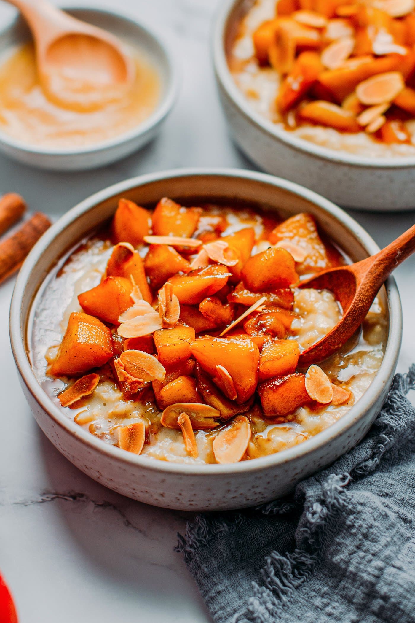 Bowl of oatmeal with gooey apple chunks and slivered almonds.