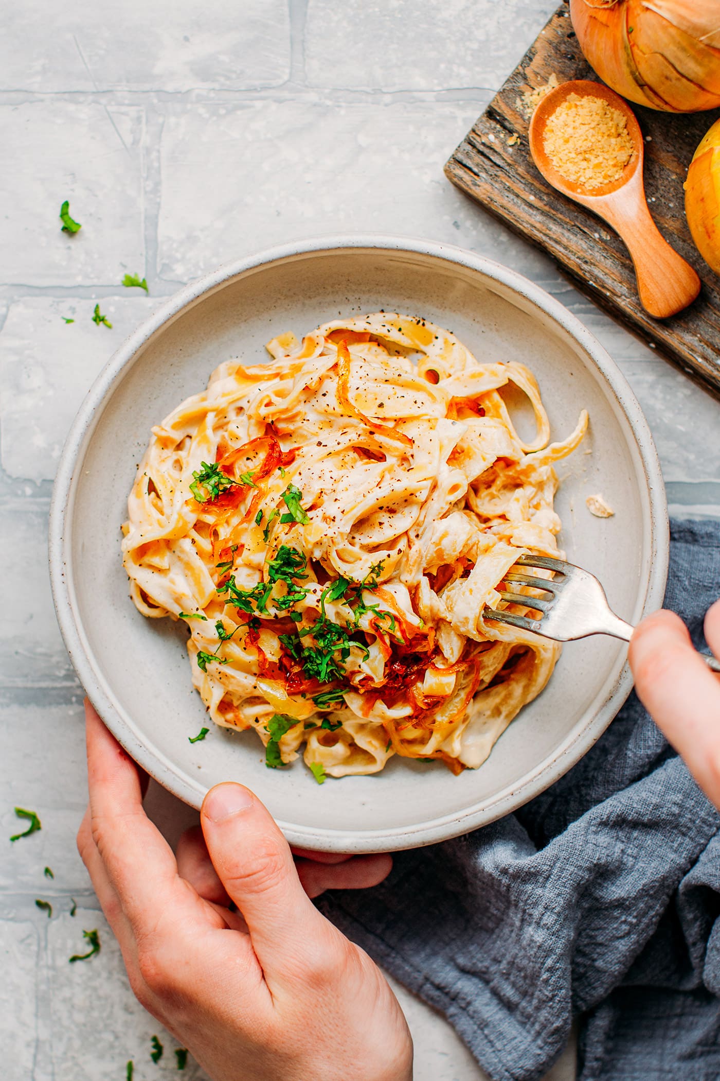 Using a fork to take some caramelized onion pasta out of a bowl.