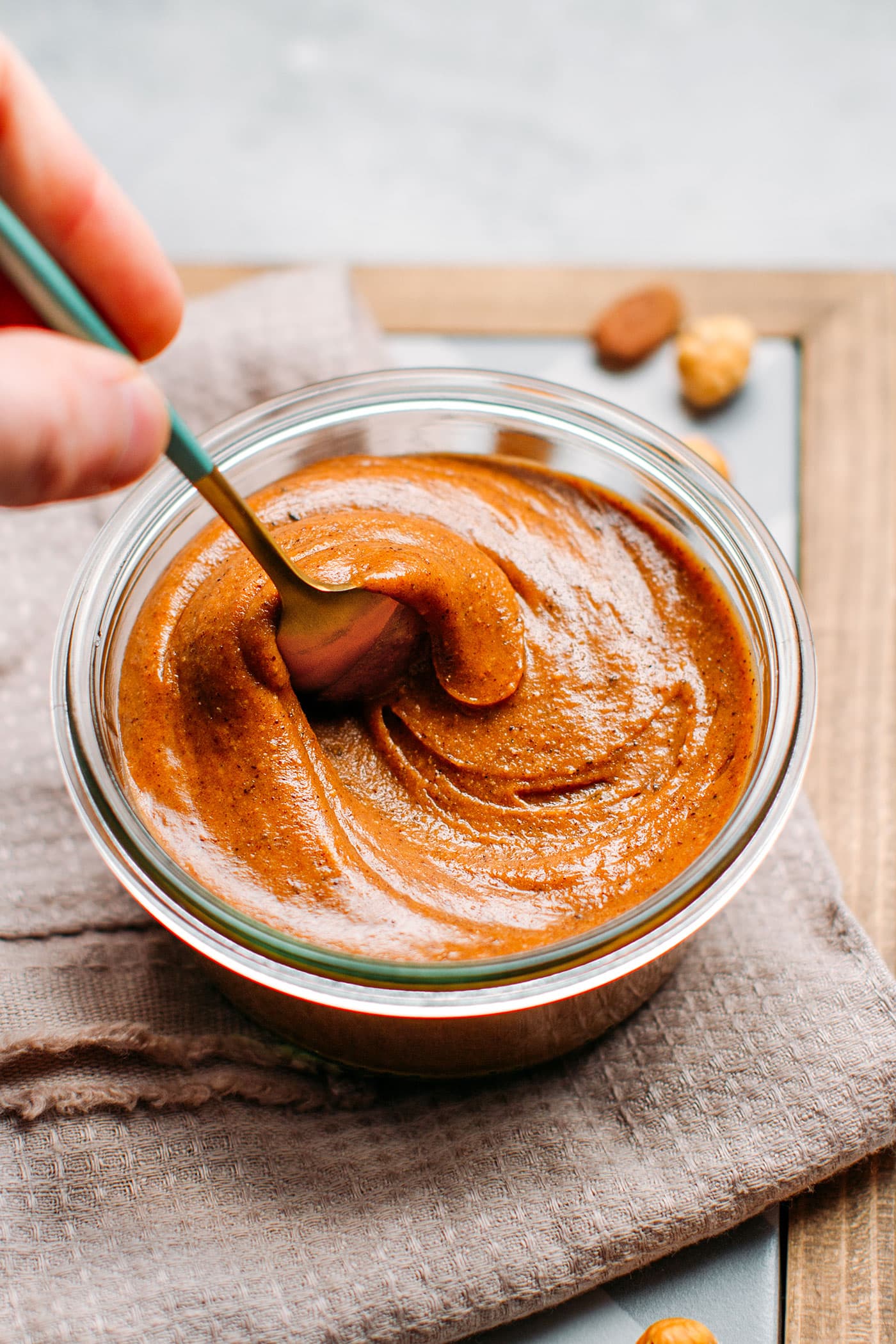 Stirring praline paste in a small glass jar.