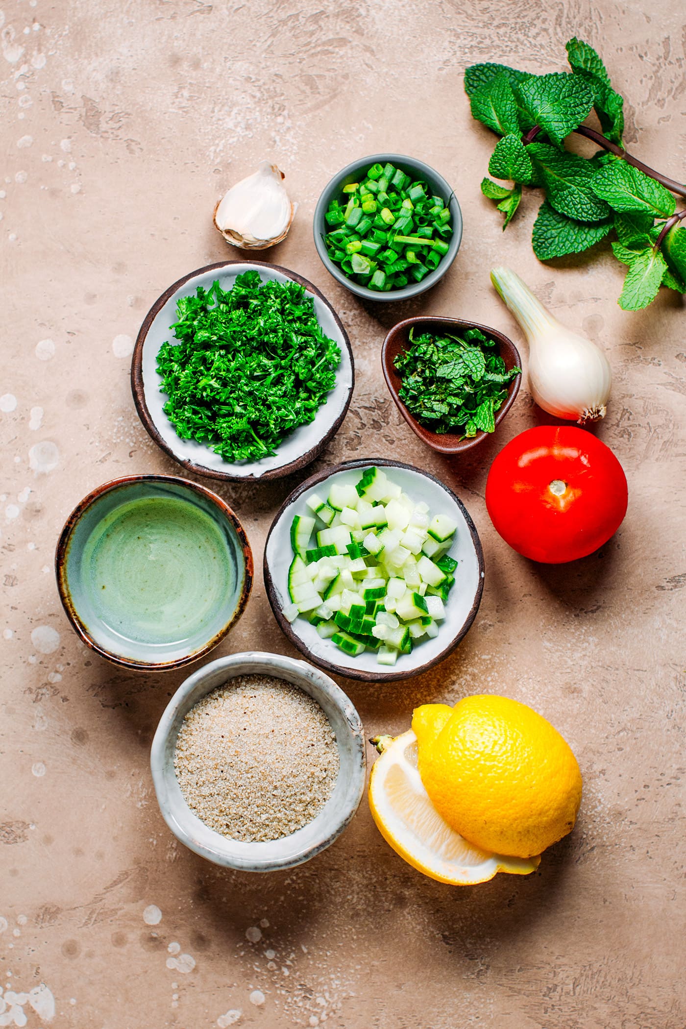 Ingredients like fonio, cucumber, tomato, parsley, mint, lemon, and garlic.