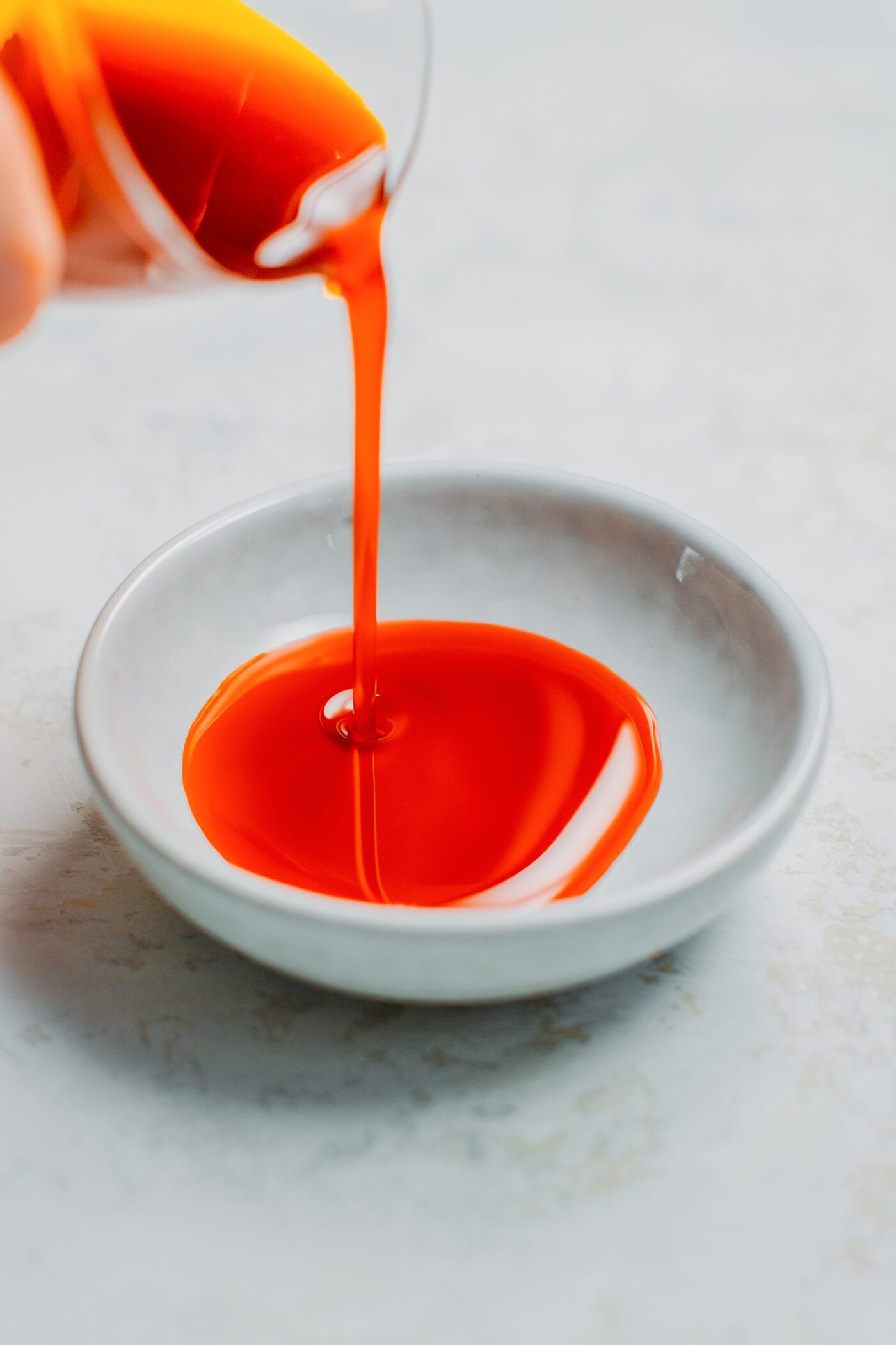 Pouring annatto oil in a bowl.