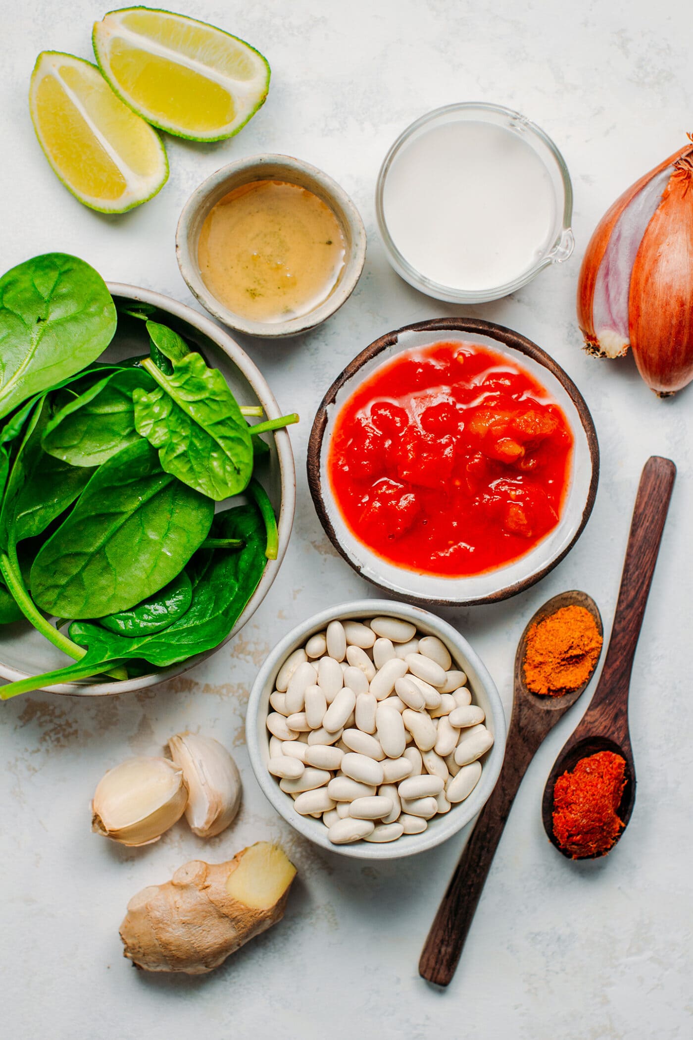 Ingredients like spinach, white beans, garlic, ginger, curry powder, and shallots.