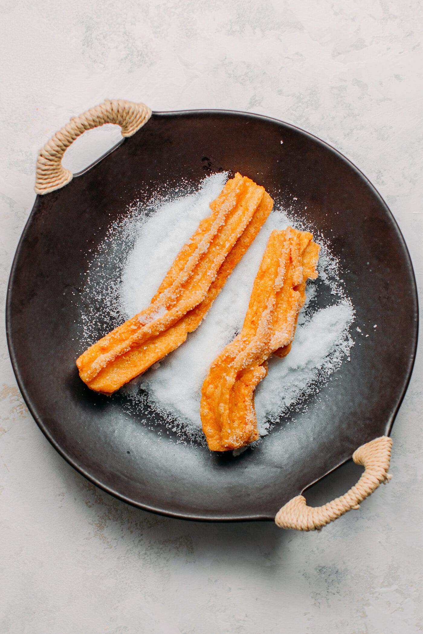 Rolling vegan churros in sugar.