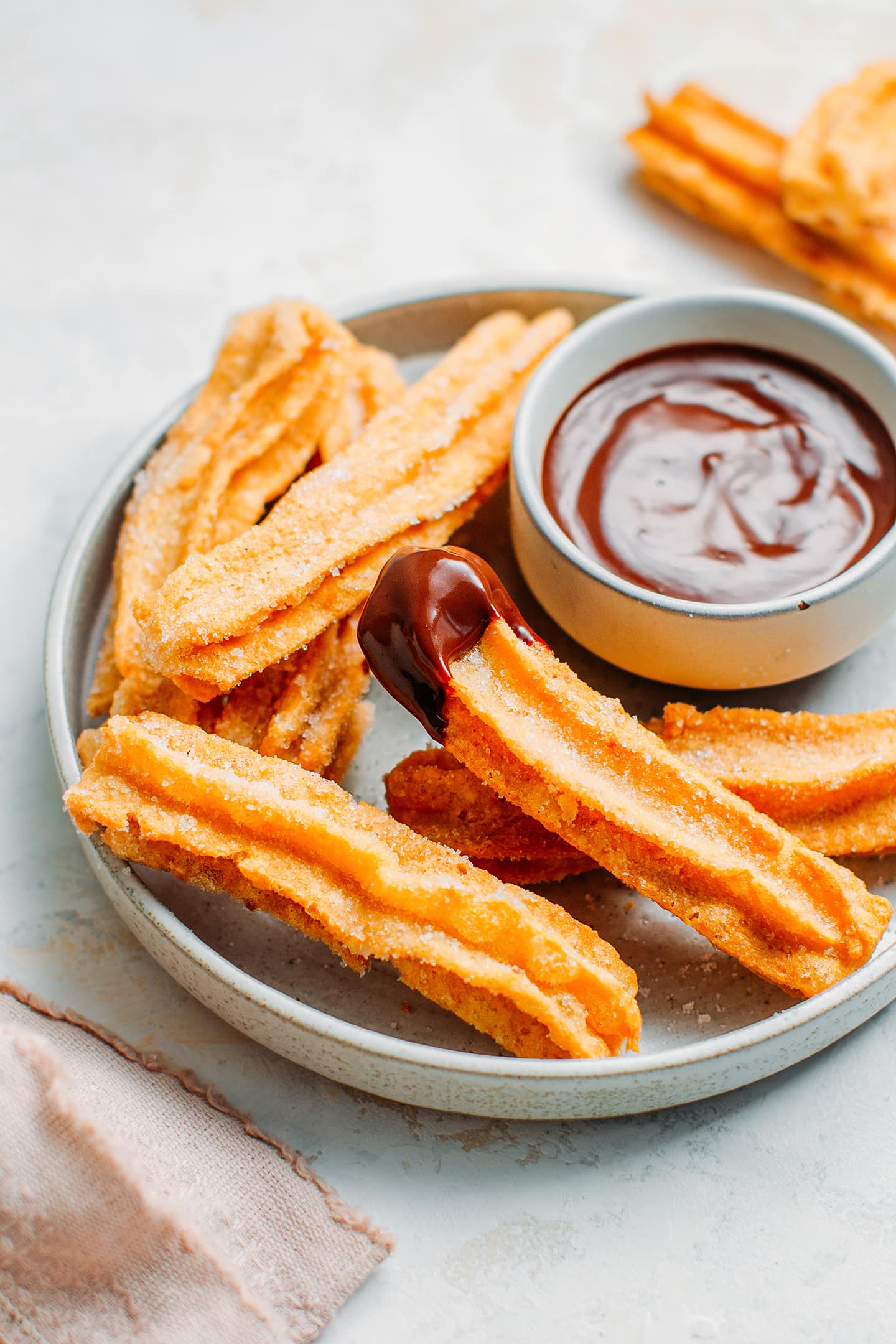 Close up of vegan churros dipping in chocolate sauce.
