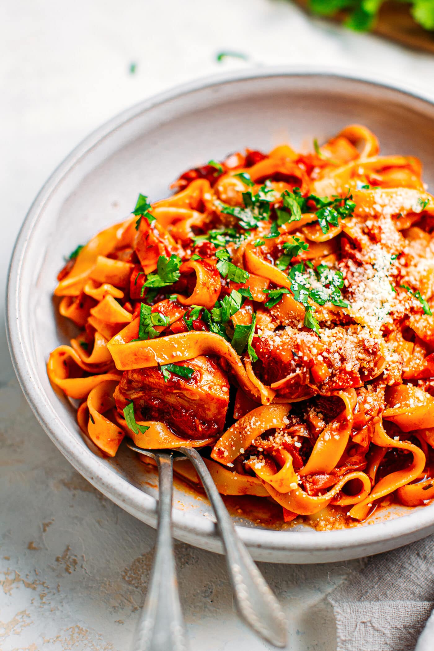 Close-up of vegan ragu pasta with jackfruit, parsley, and parmesan.