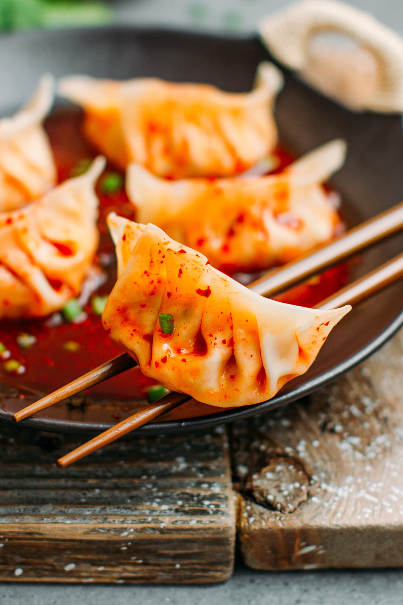 Kimchi dumpling on a pair of chopsticks.