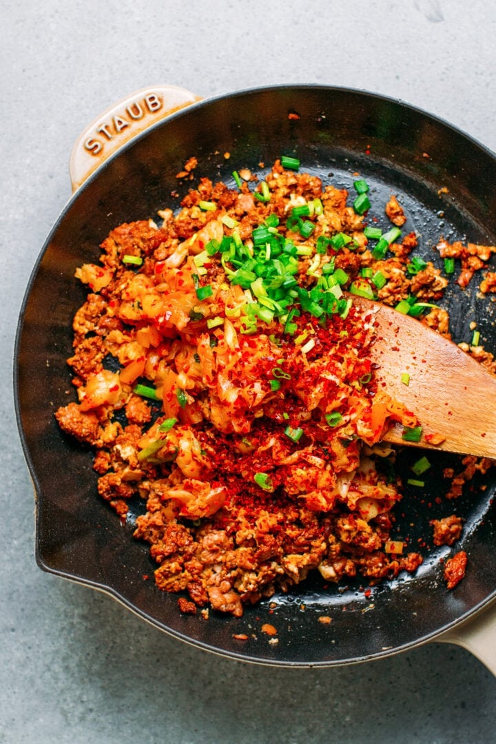 Tofu, kimchi, and green onions in a skillet.