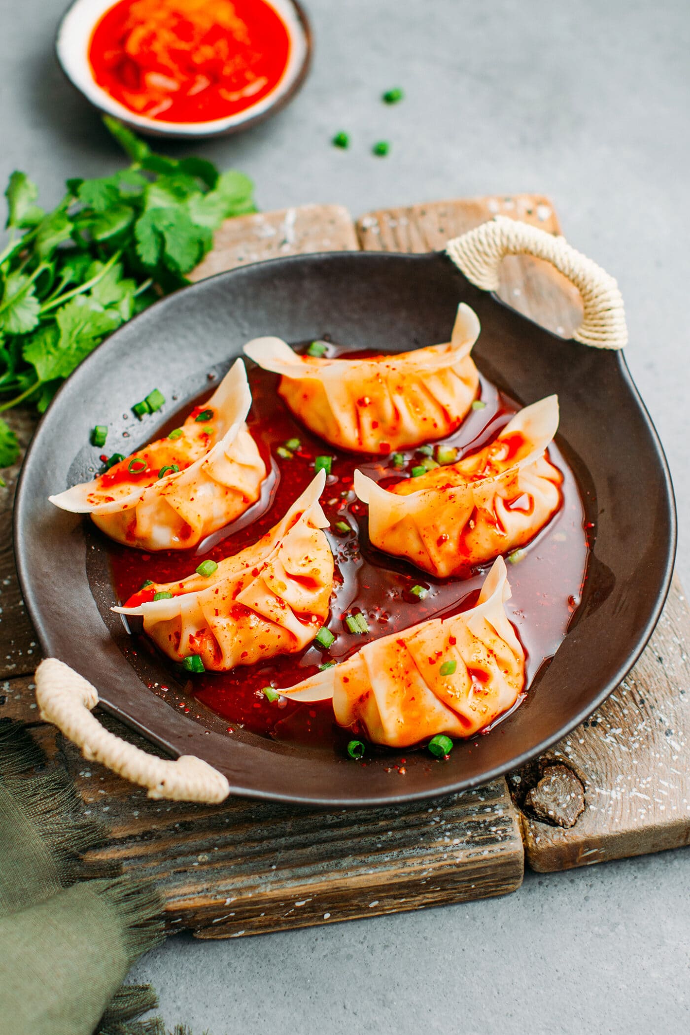 Kimchi dumplings topped with green onions in a plate.