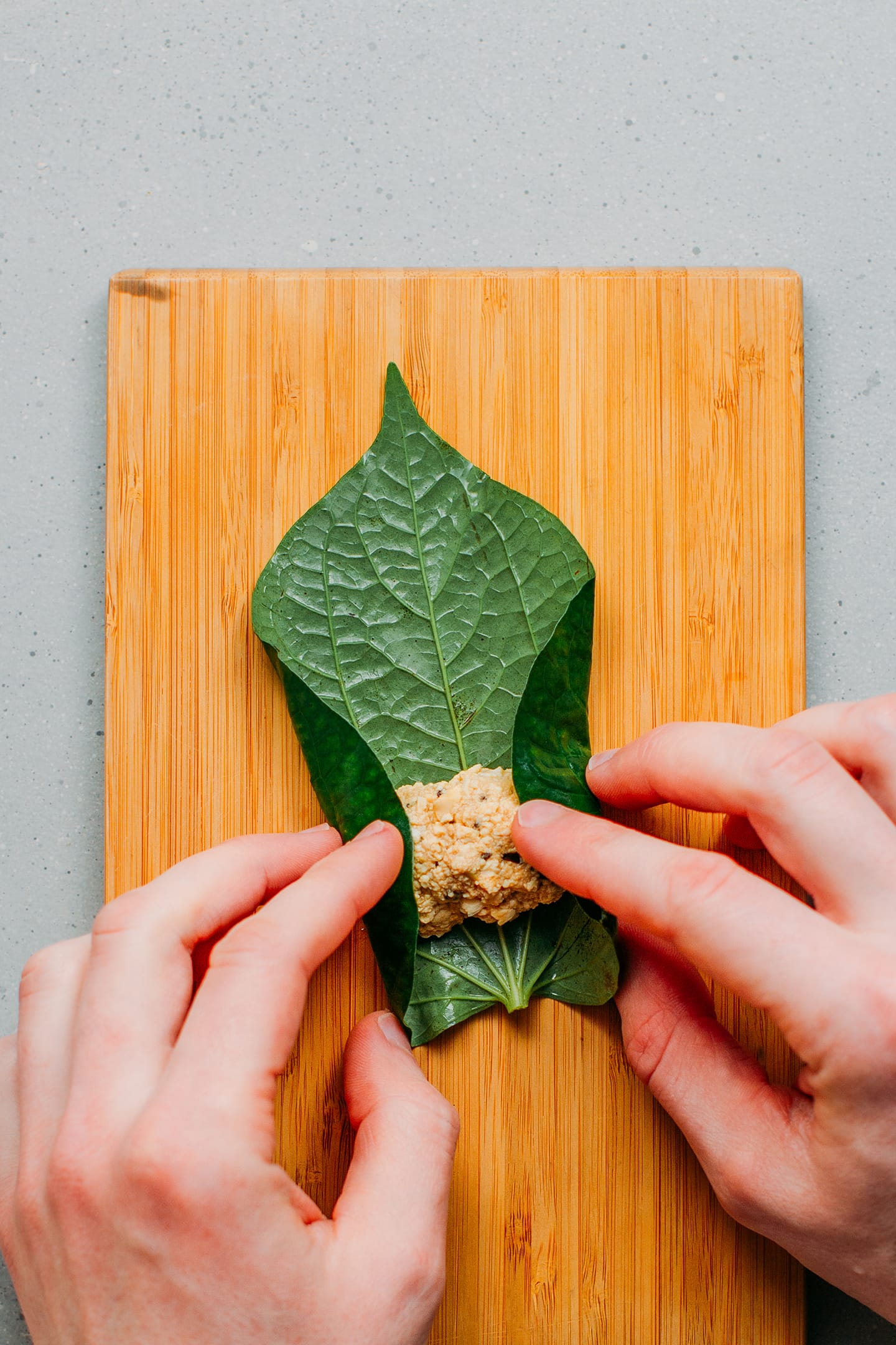 Rolling up a tofu filling in betel leaves.