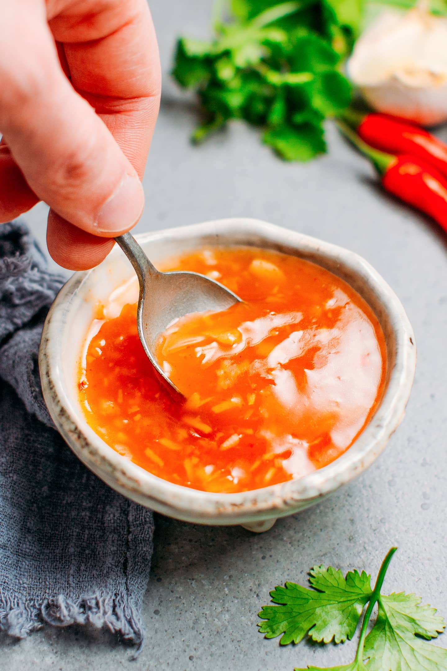 Dipping a spoon into a bowl of sweet and sour sauce.