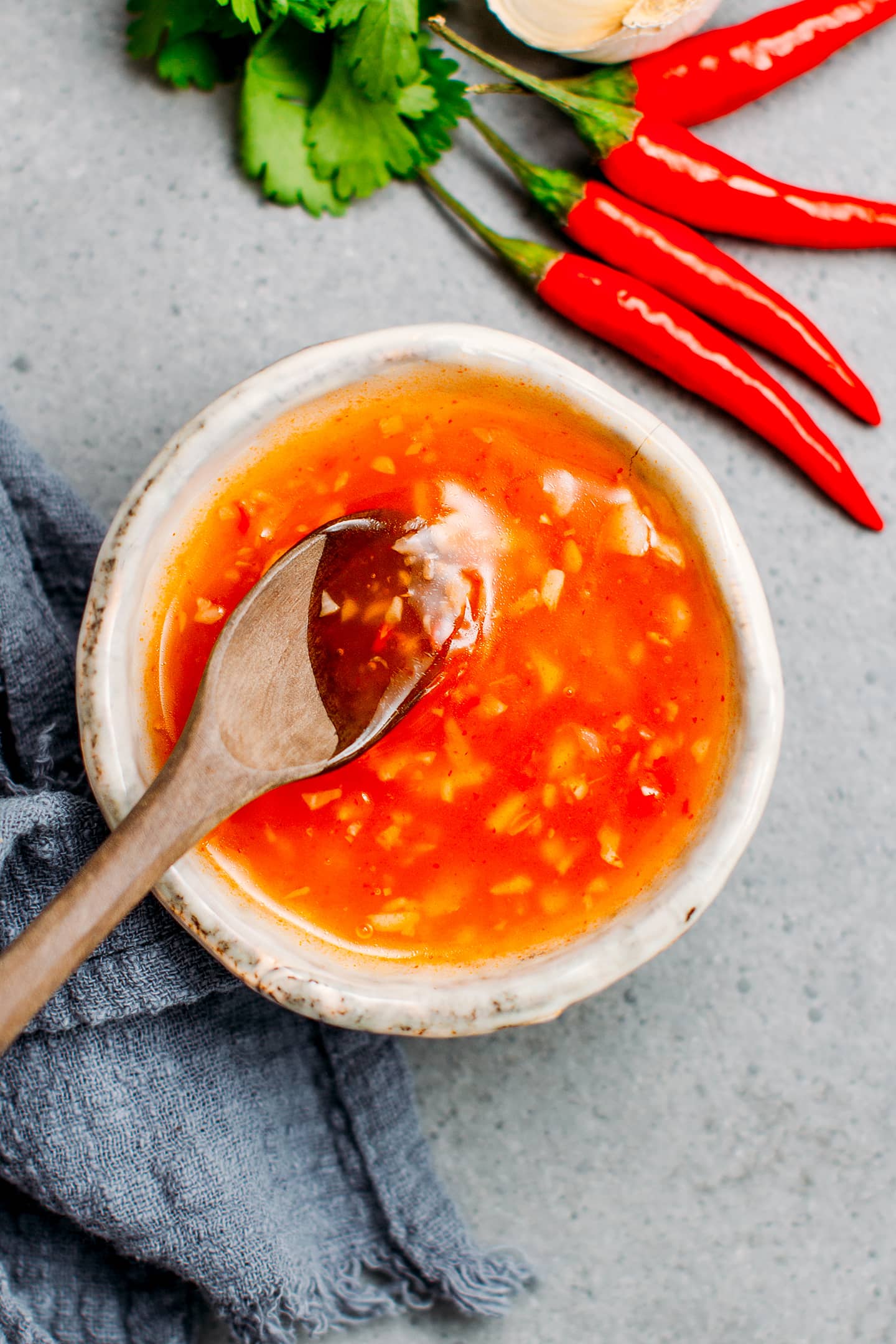 Wooden spoon in a small bowl containing sweet and sour chili sauce.