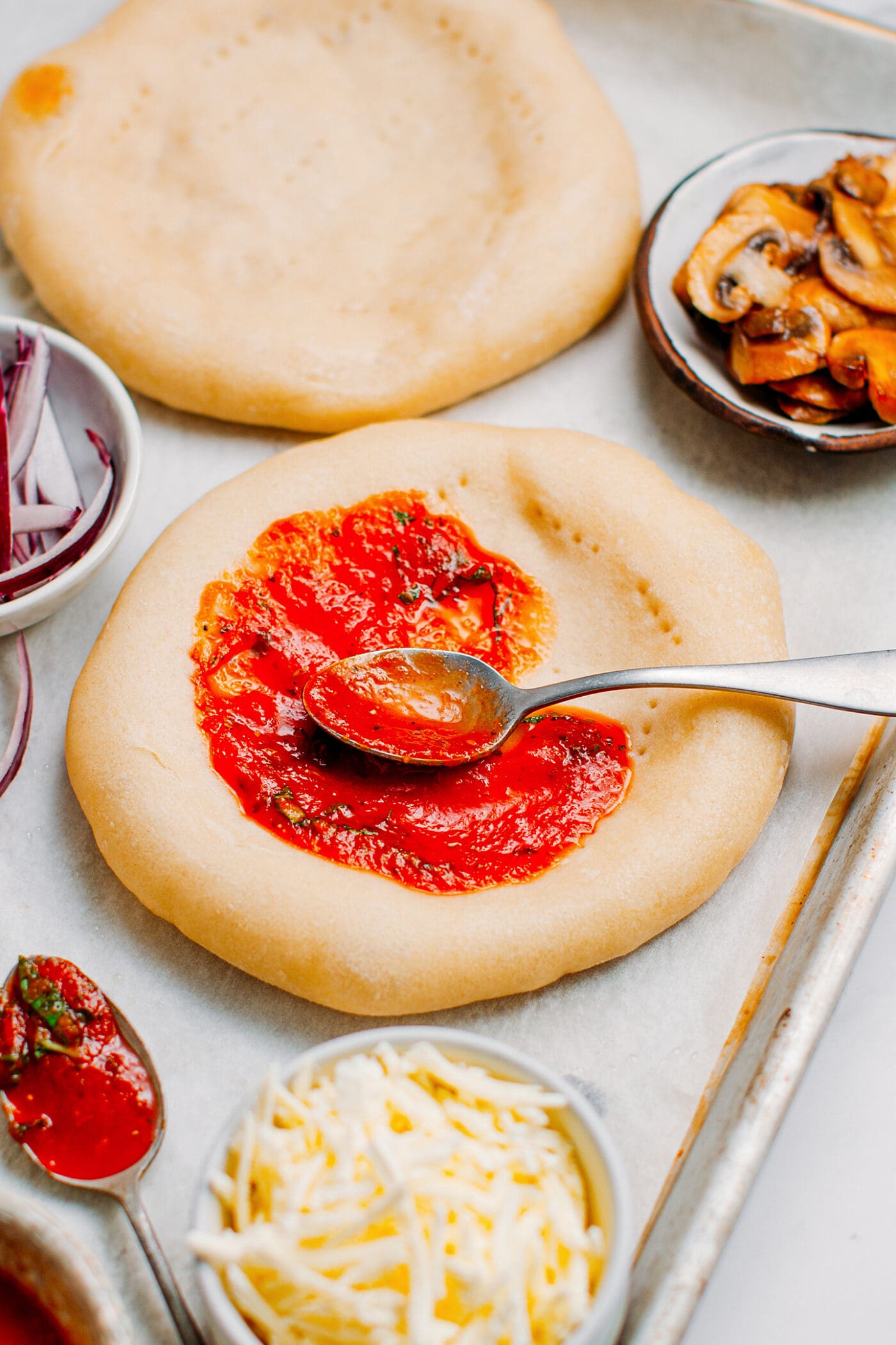Spreading tomato sauce on a pizza crust.