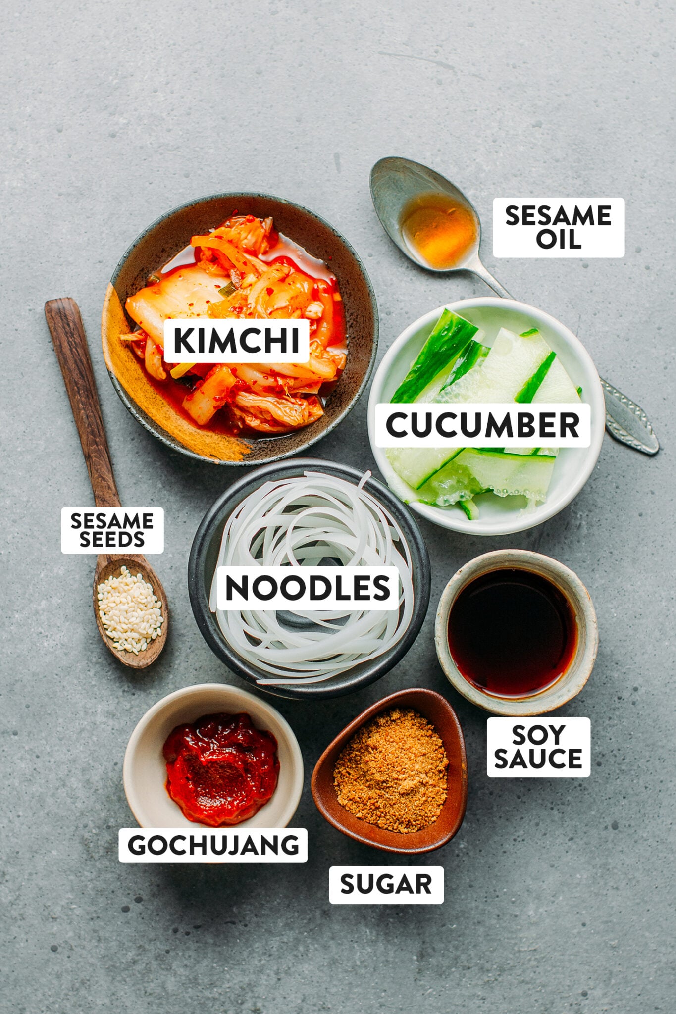 Ingredients like kimchi, noodles, gochujang, soy sauce, sugar, cucumber.