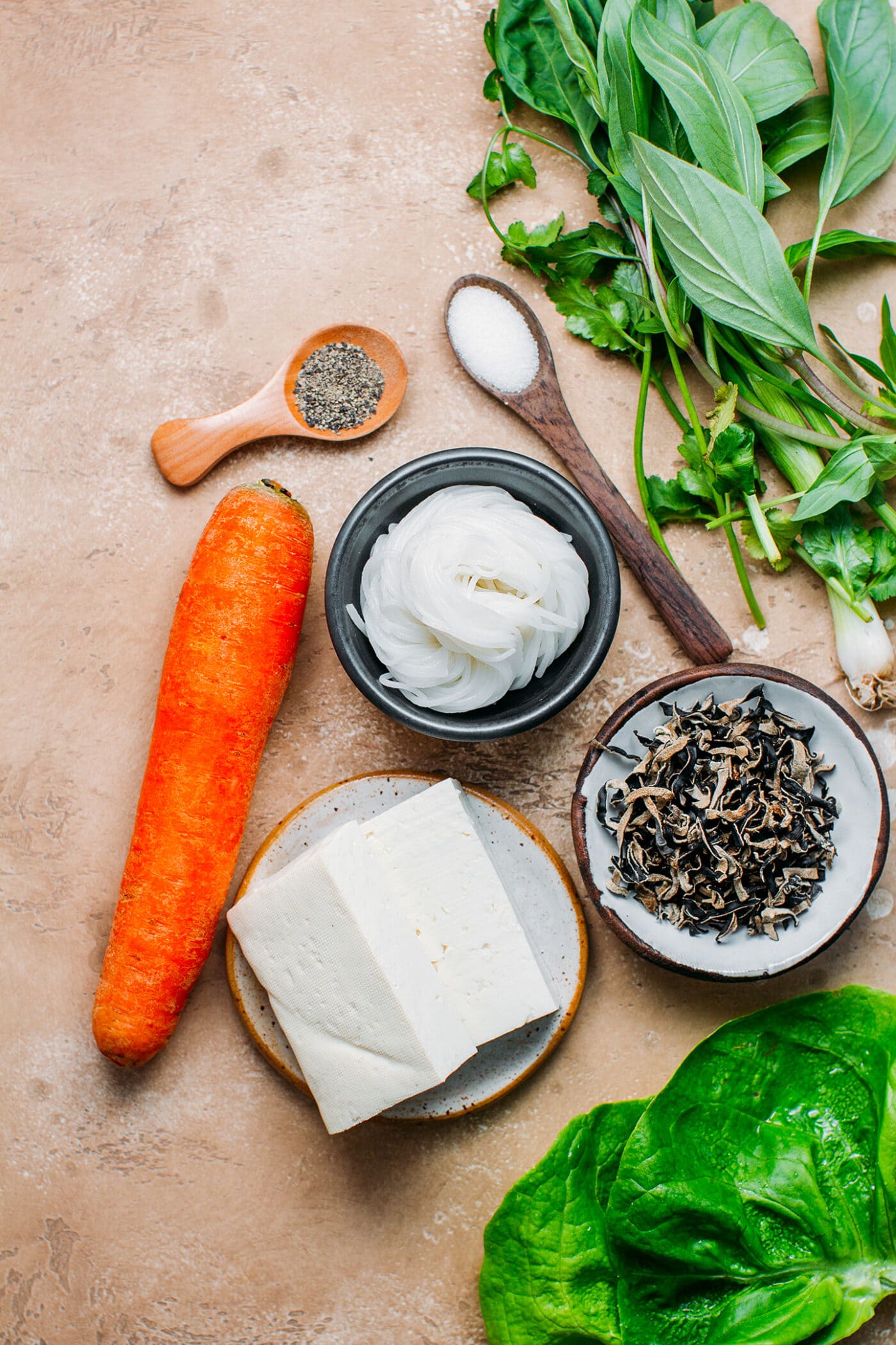 Ingredients like carrot, rice noodles, pepper, tofu, lettuce.