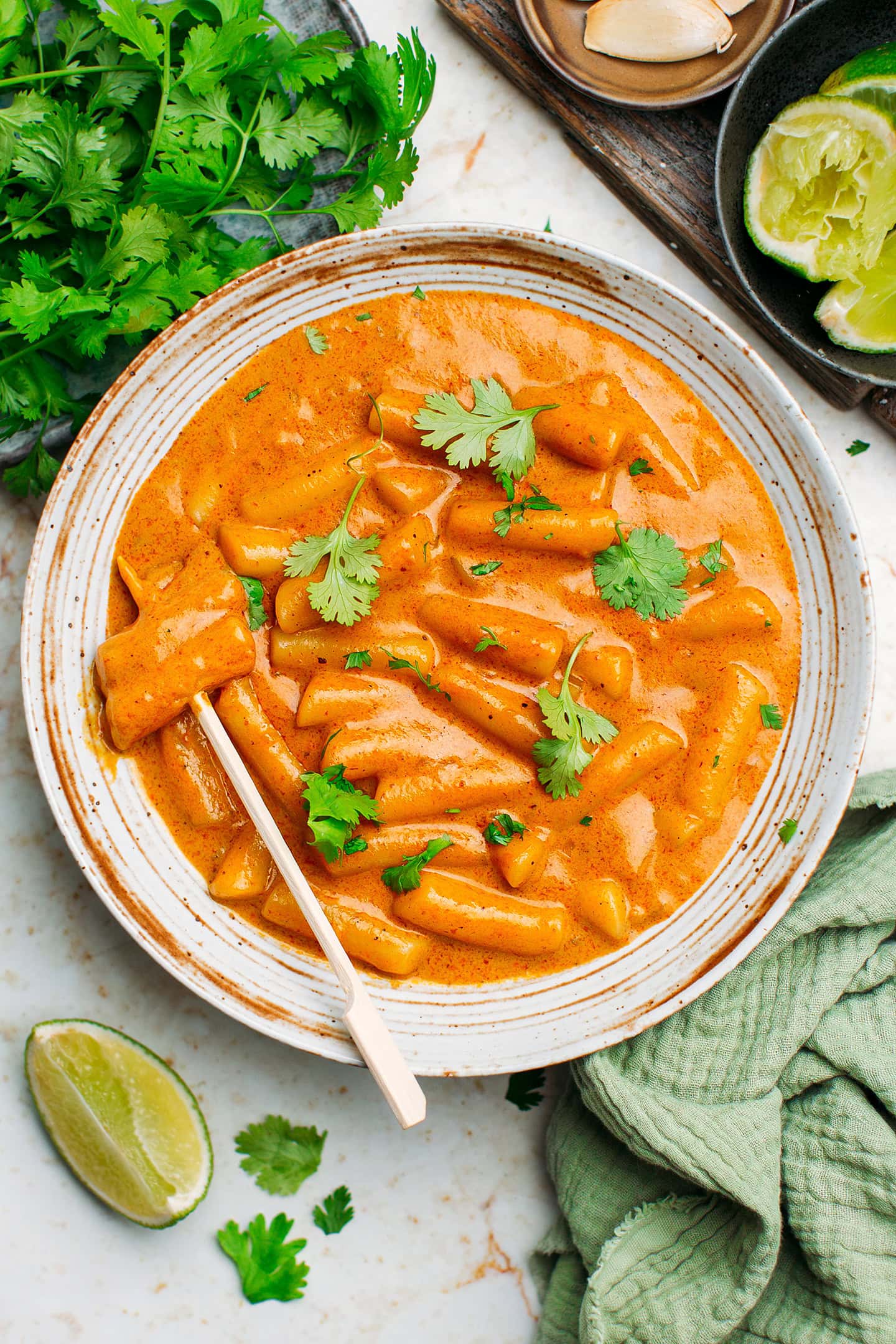 Sliced rice cakes in a red curry sauce.