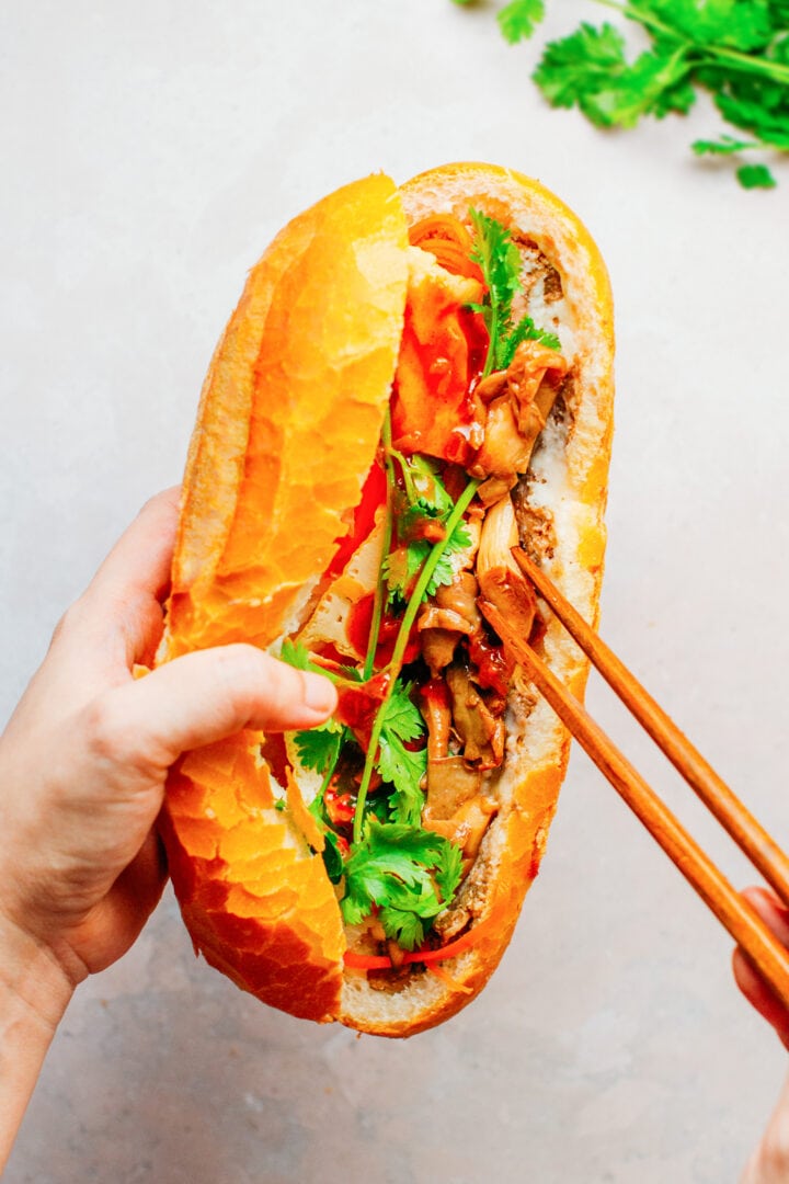 Filling vegan banh mi sandwich with sautéed mushrooms.